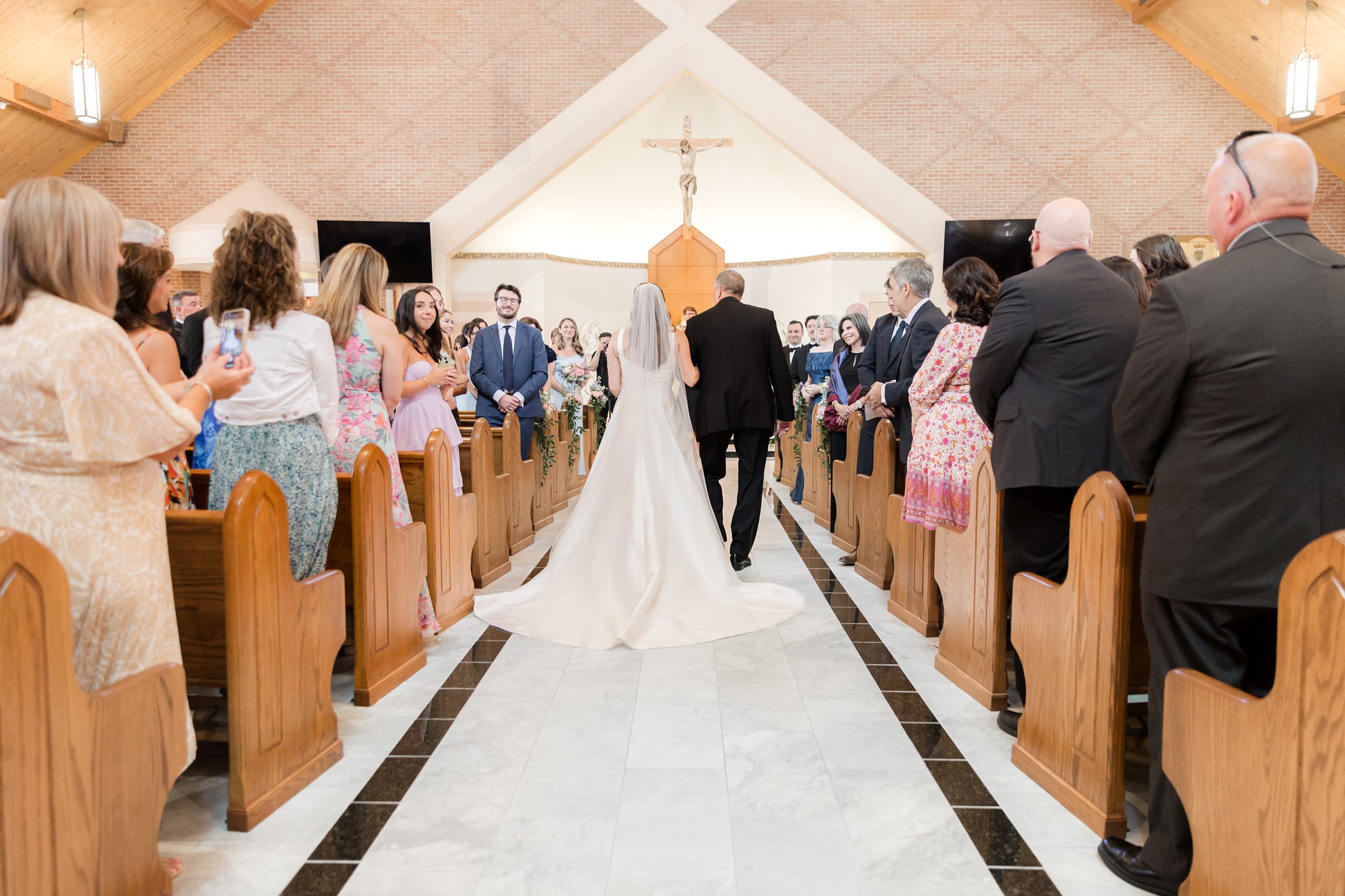 a back shot of bride's father walking her down the aisle 