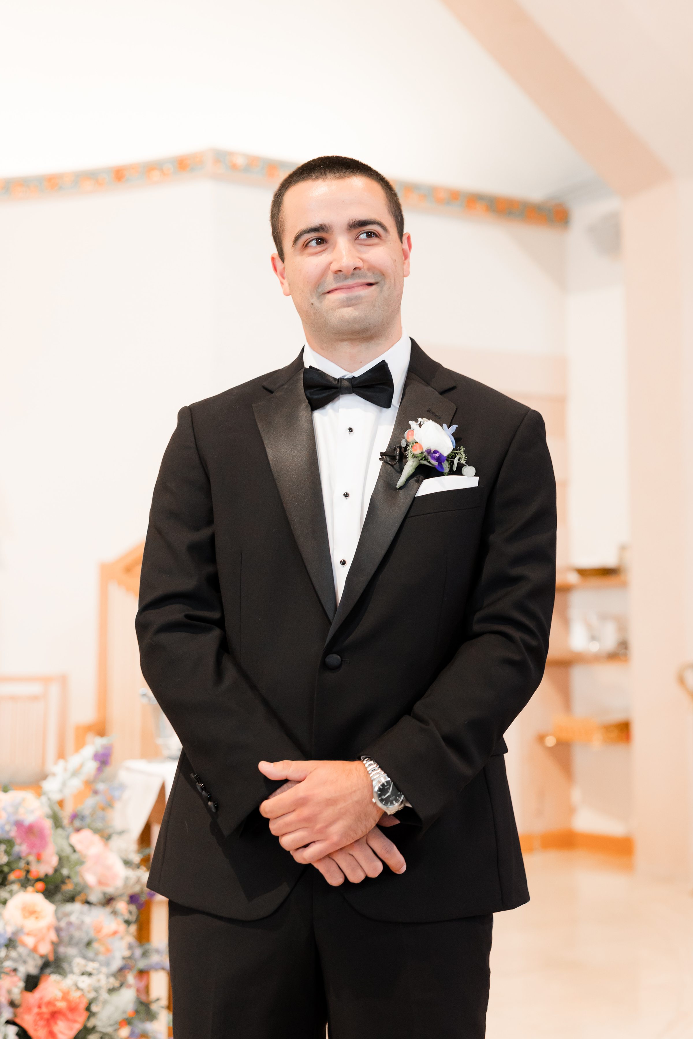 groom smiling while looking at the bride while her father walk her down the aisle 