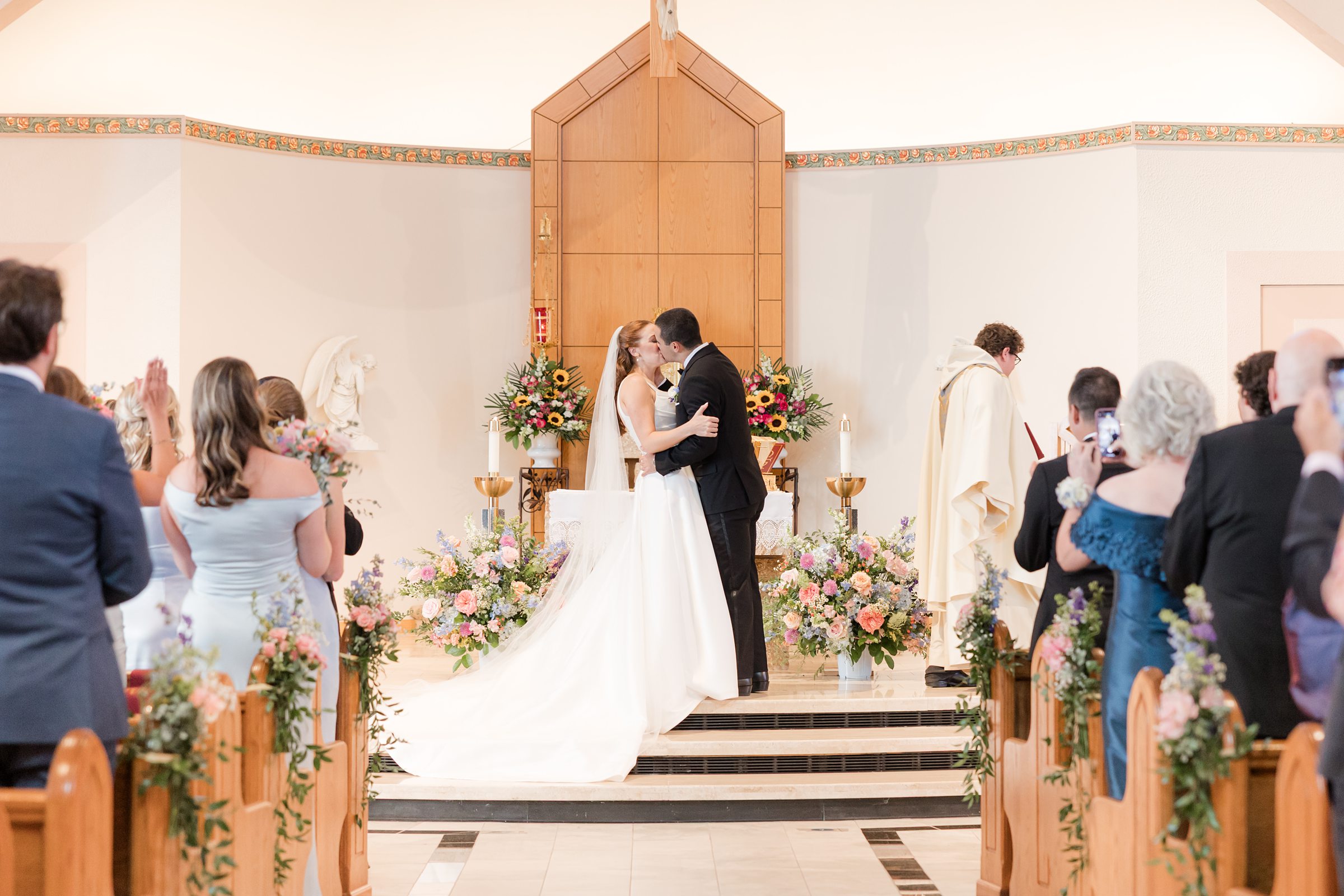 a landscape picture of bride and groom kissing at the altar at the ceremony