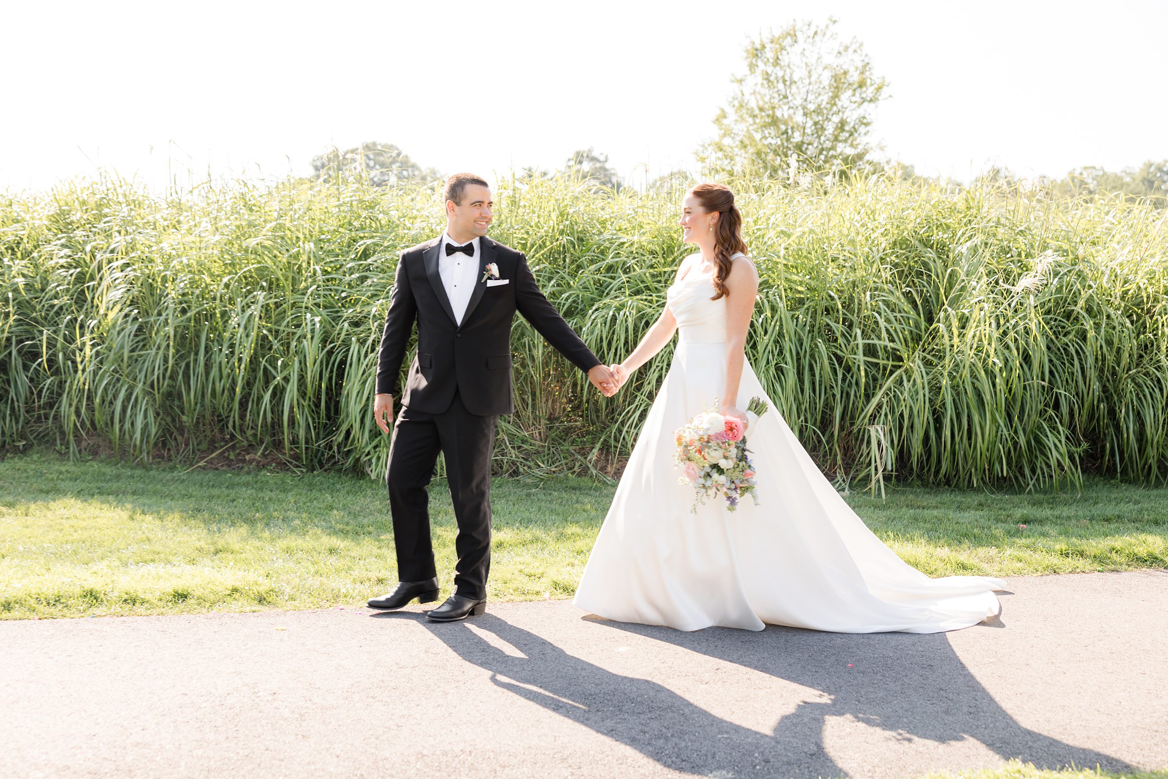 landscape picture of the bride and groom holding hands while the bride is holding the flower bouquet 