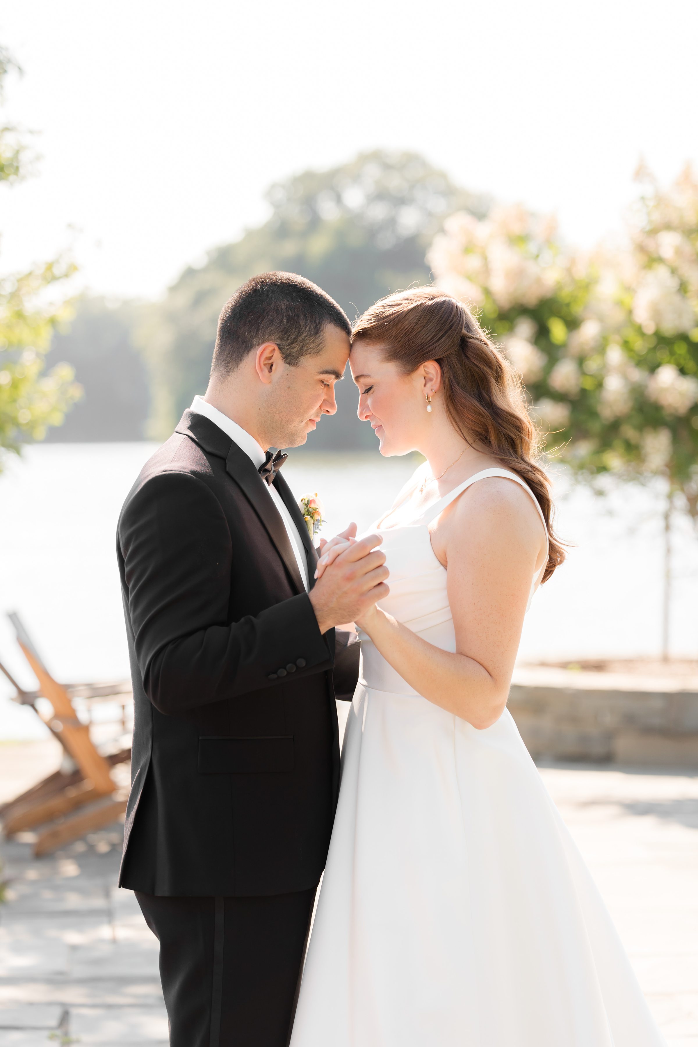 a photo of bride and groom, holding each other's hands while their heads are against each other