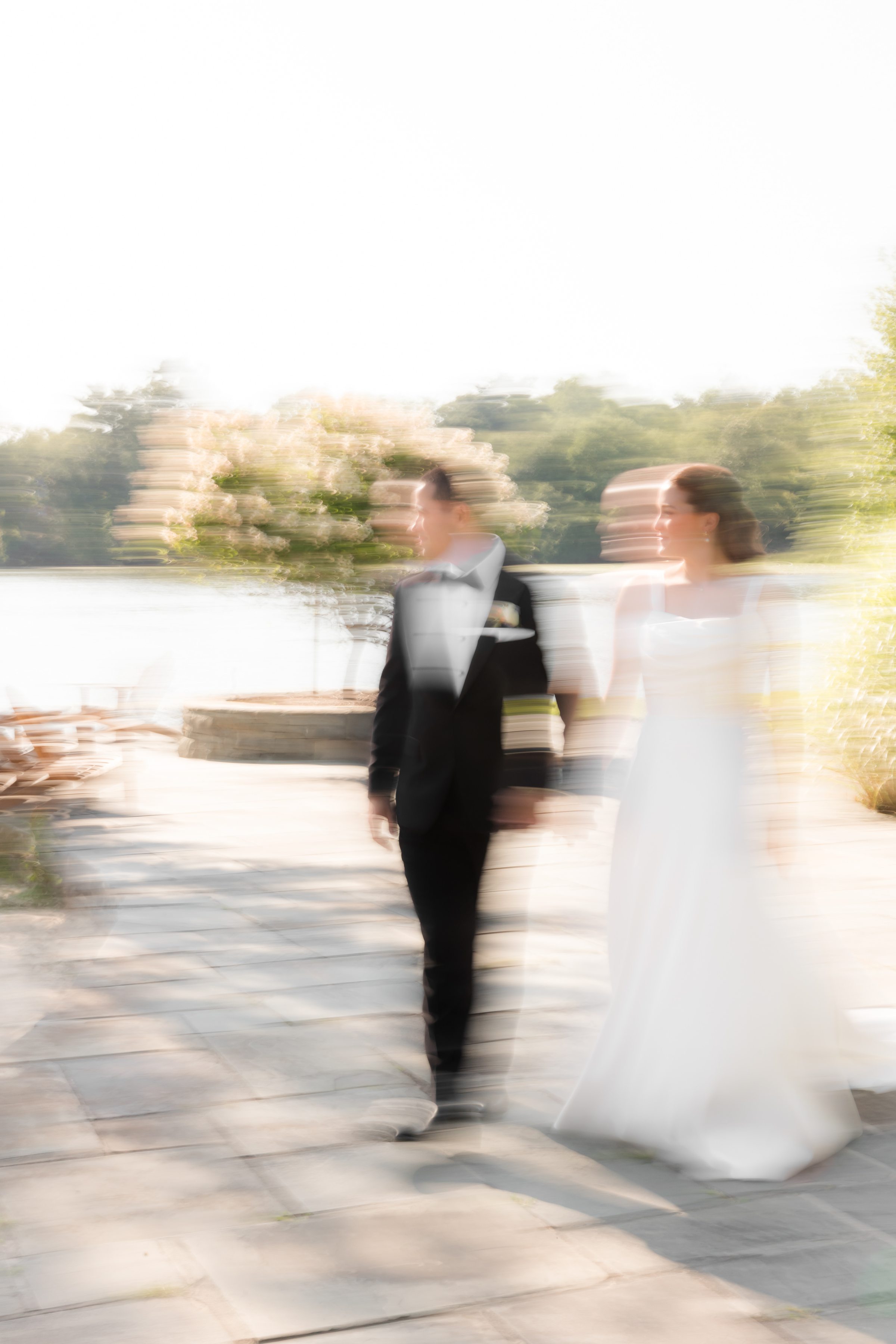a candid blurry picture of bride and groom walking by the lake 