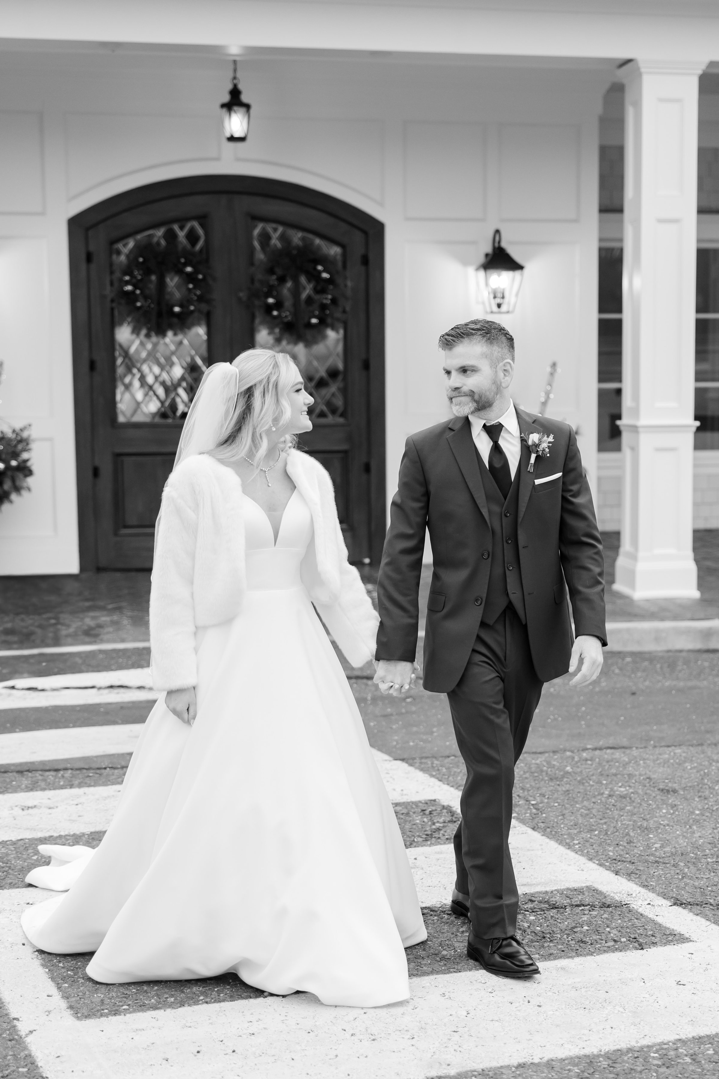 Bride and groom walk together, exchanging loving glances in a timeless black and white moment.