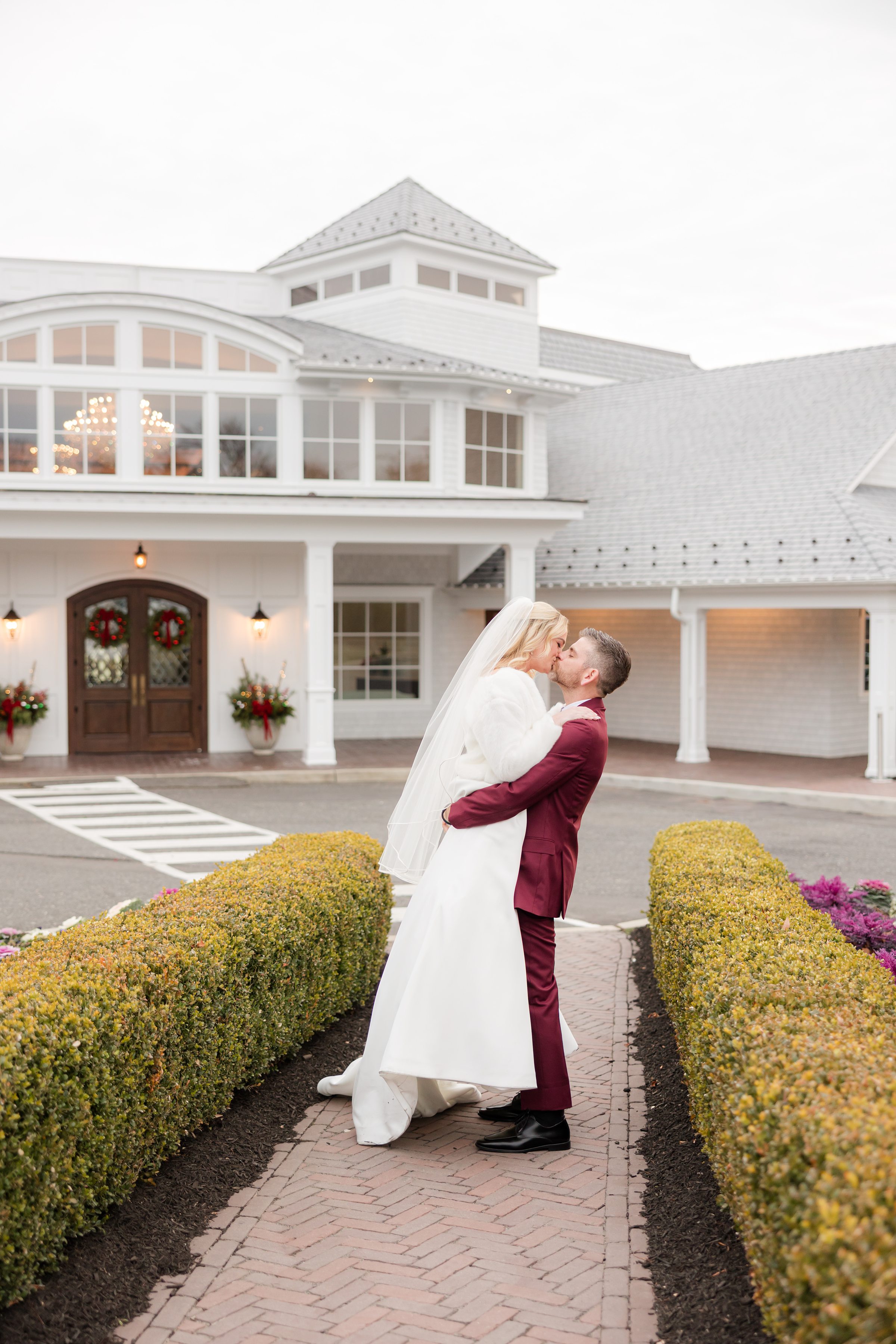 Groom lifts the bride as they share a kiss in front of their elegant wedding venue.