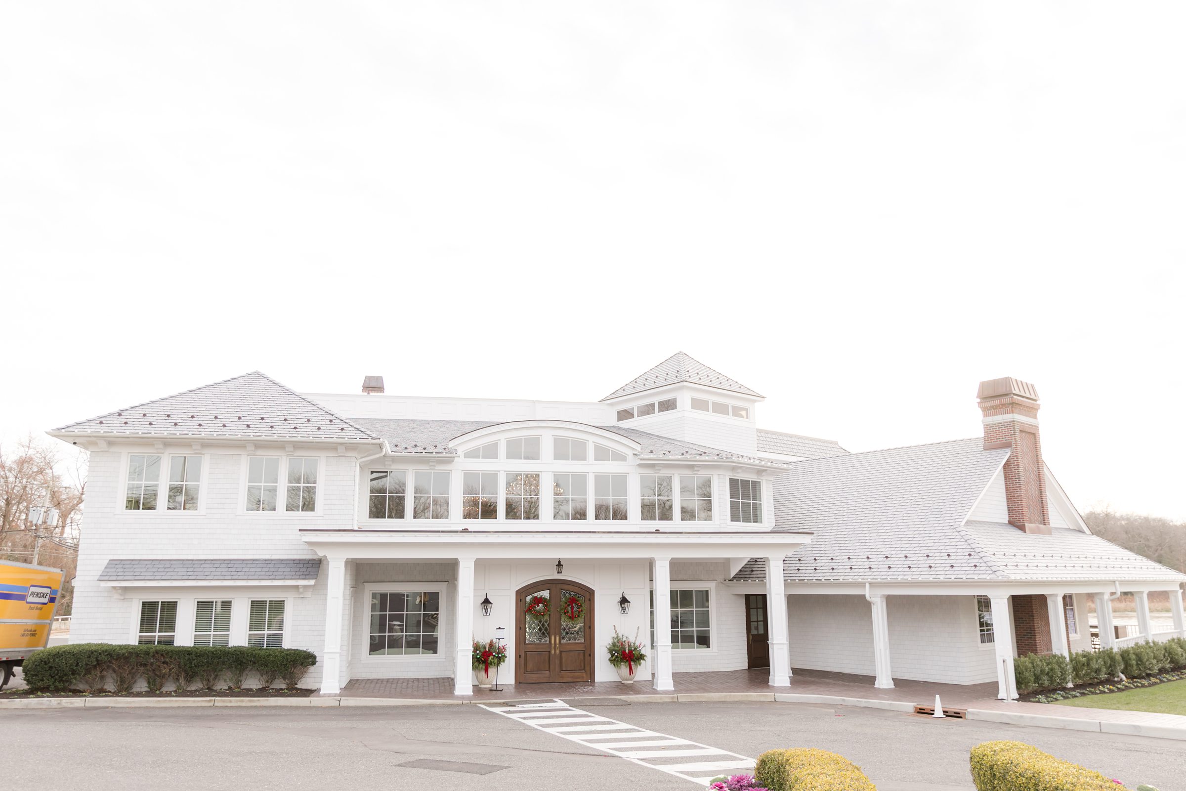 Charming white venue dressed in holiday wreaths and soft winter light, setting the scene for a romantic celebration.