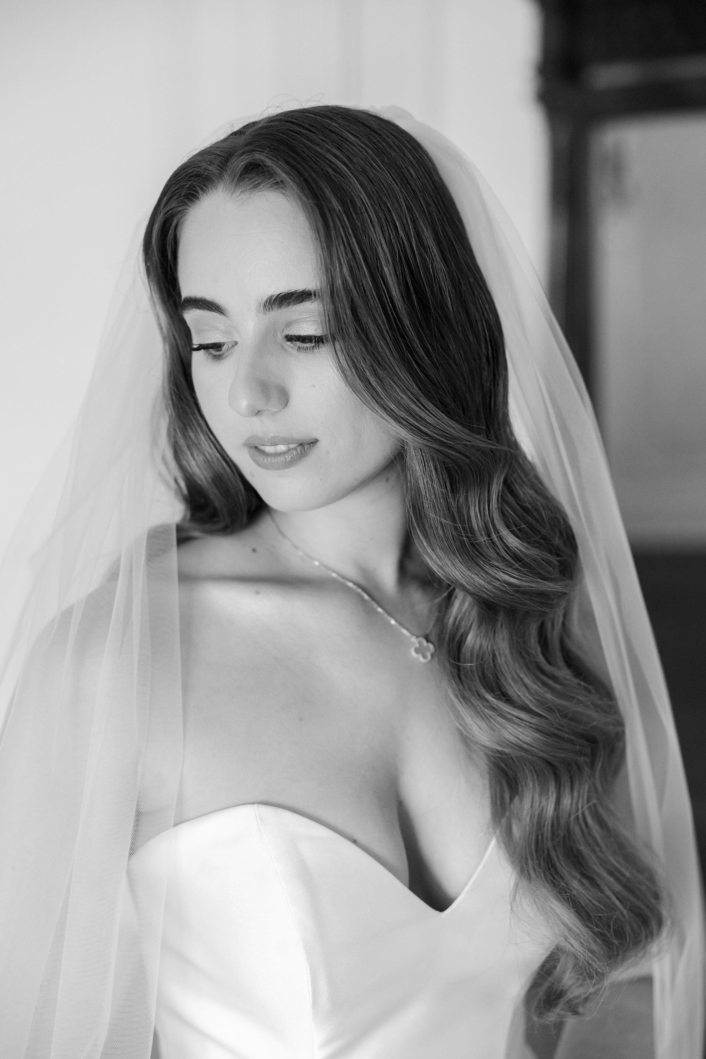 Black and white portrait of the bride looking down, with hollywood waves hairstyle while wearing a veil