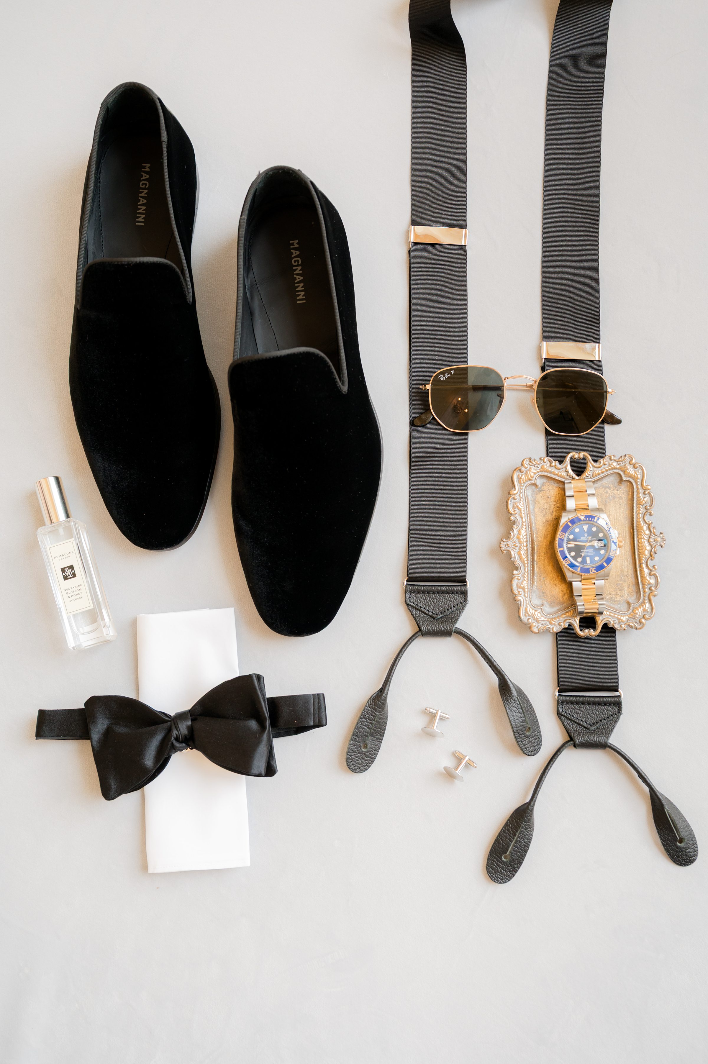 Groom's details, black velvet shoes, satin bow, suspender and sunglasses with black and gold details. Perfume, and gold watch
