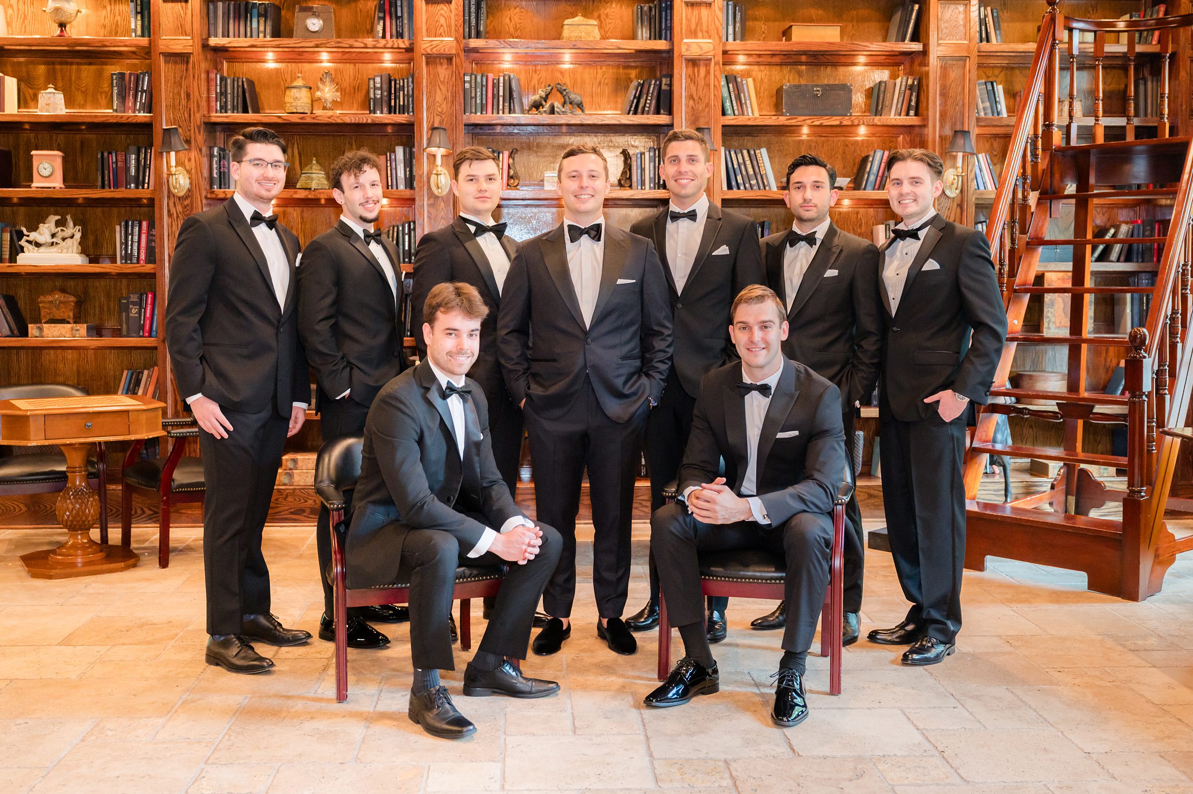 Groom and groomsmen formals, standing and sitting in a wooden room