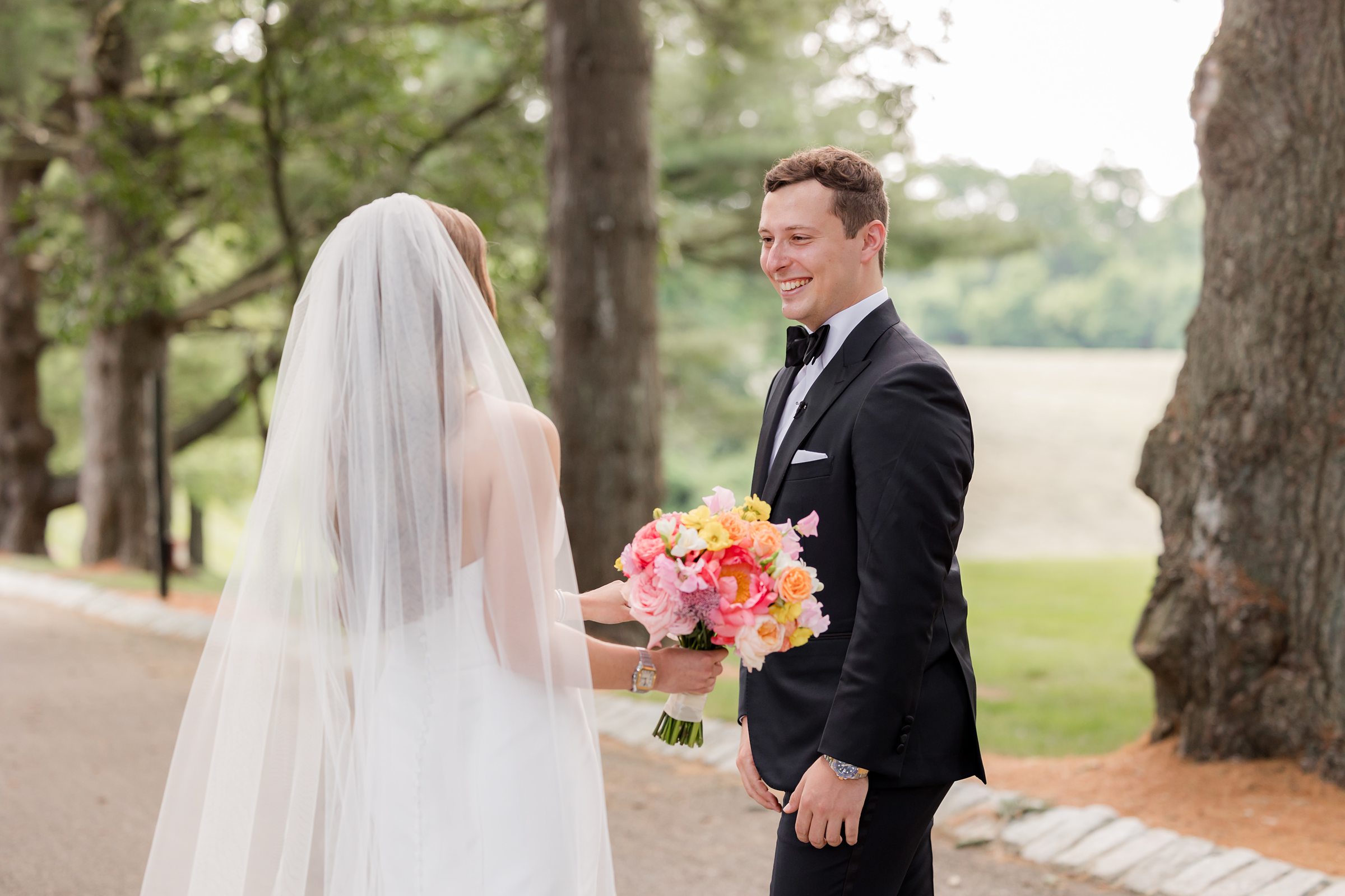 Groom turning to see the bride for the first look. Bride is holding a bouquet with summer palette