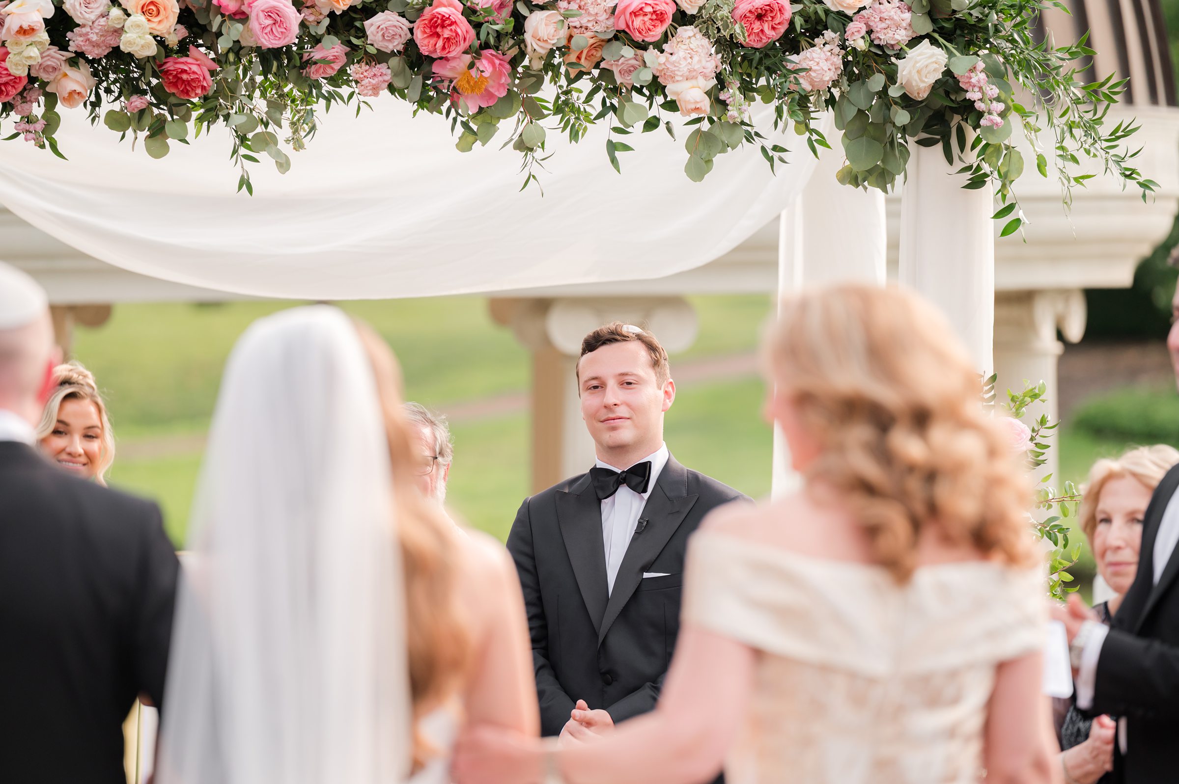 Groom looking at the bride while her parents walk her down the aisle