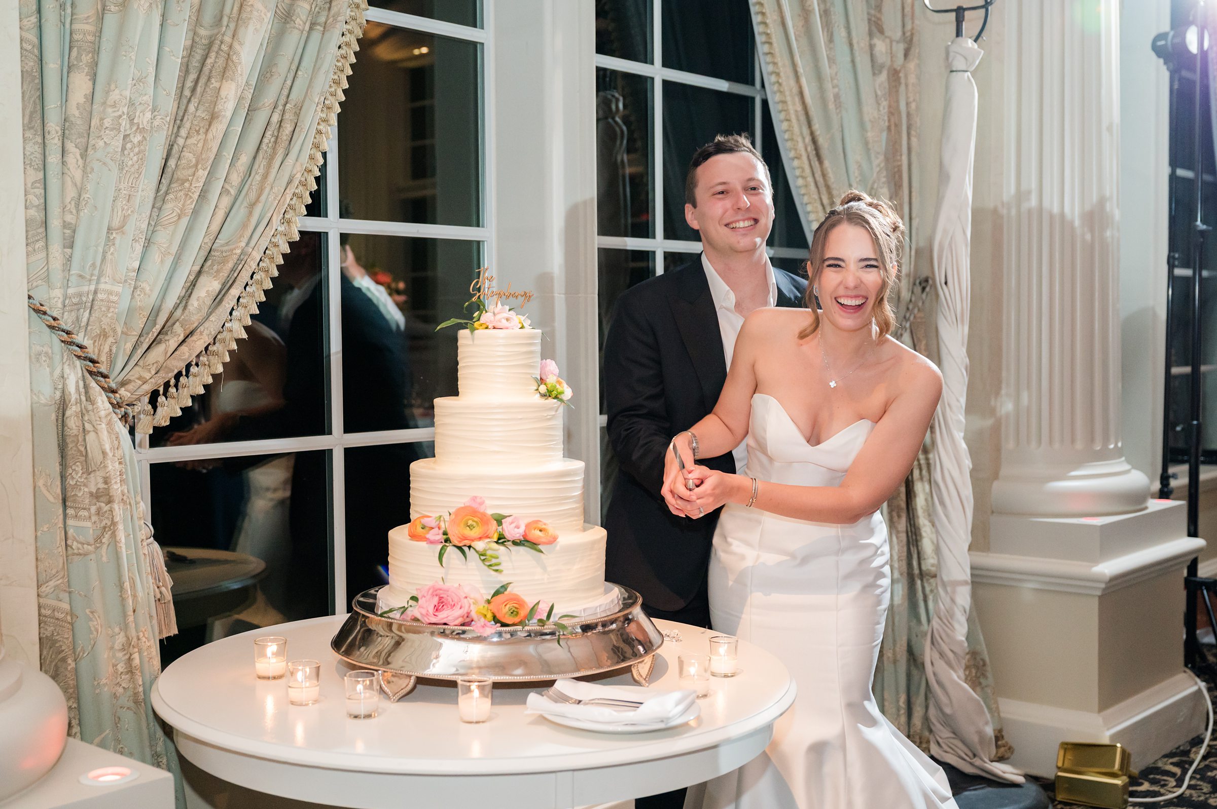 Bride and groom about to slice the cake together while smiling