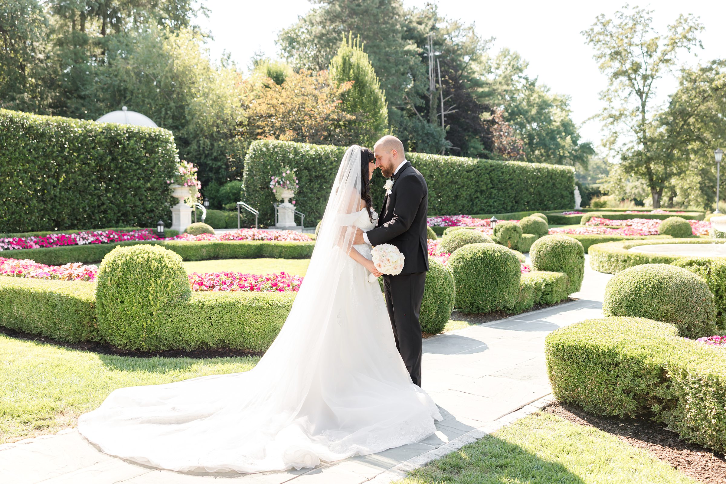 landscape picture of groom and bride in the garden, with their heads leaning against each other 