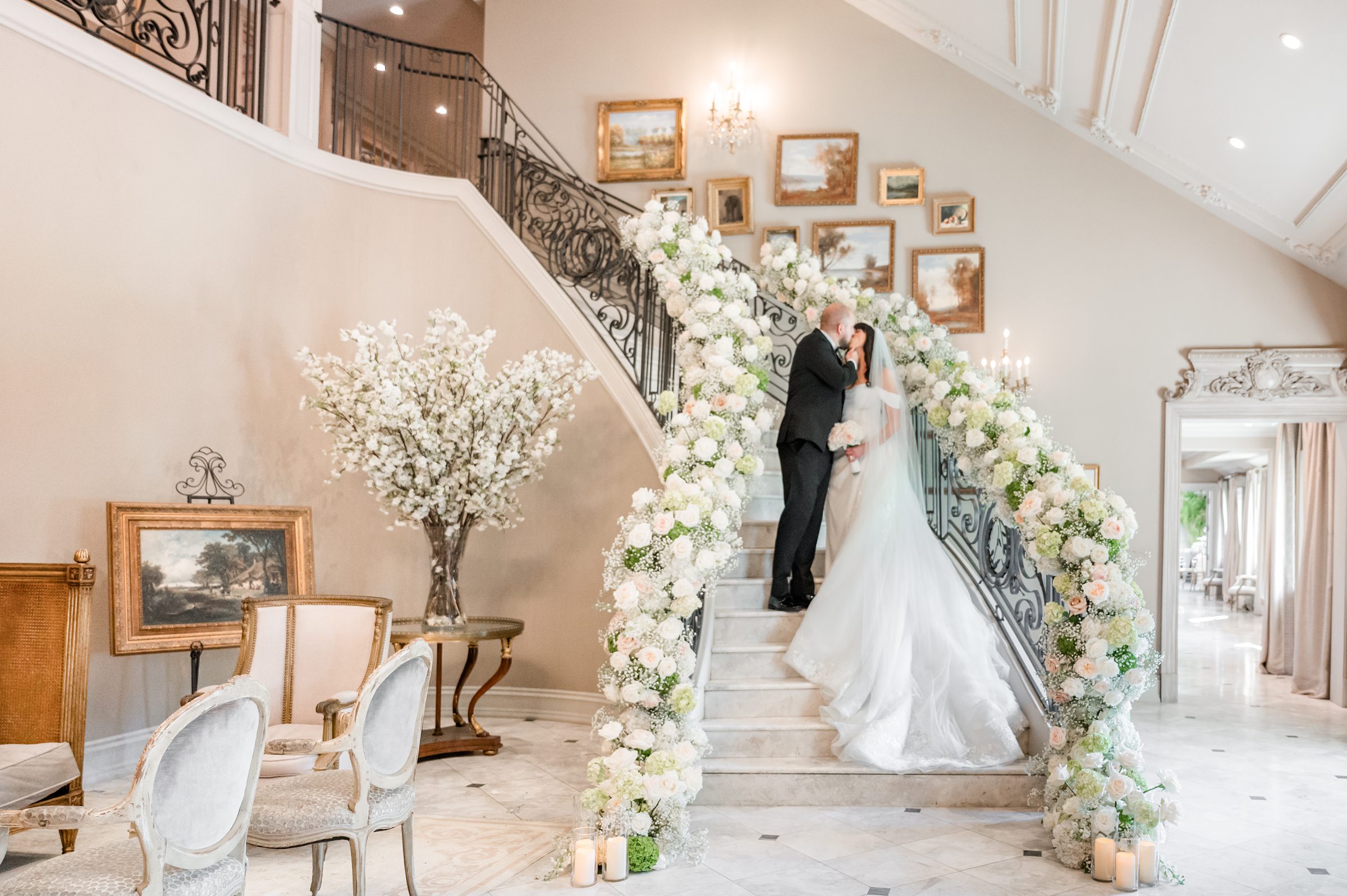 groom and bride kissing at the stairs with flower decoration in reception hall
