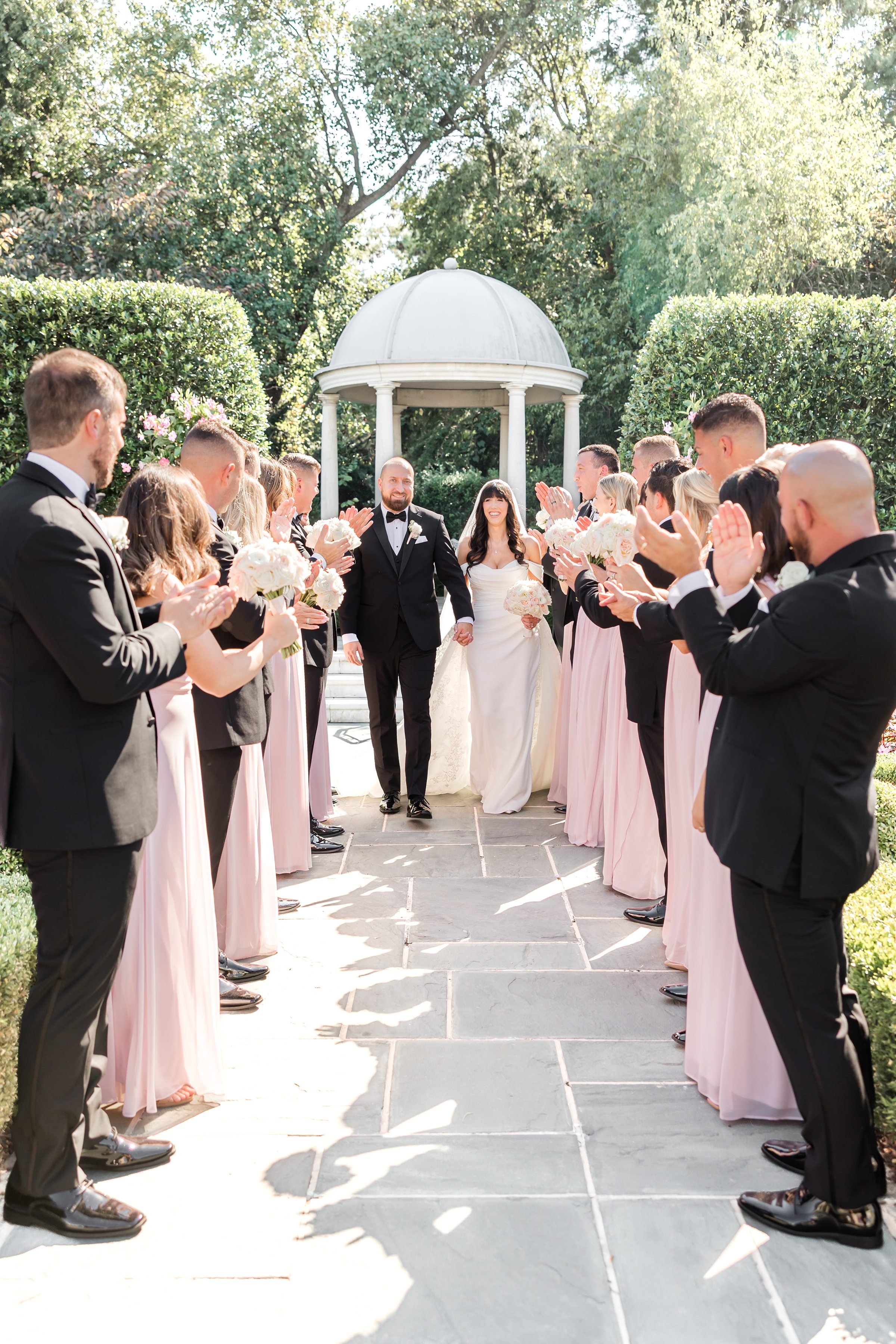 bride and groom walking down the aisle while bridesmaids and groomsmen are clapping and cheering
