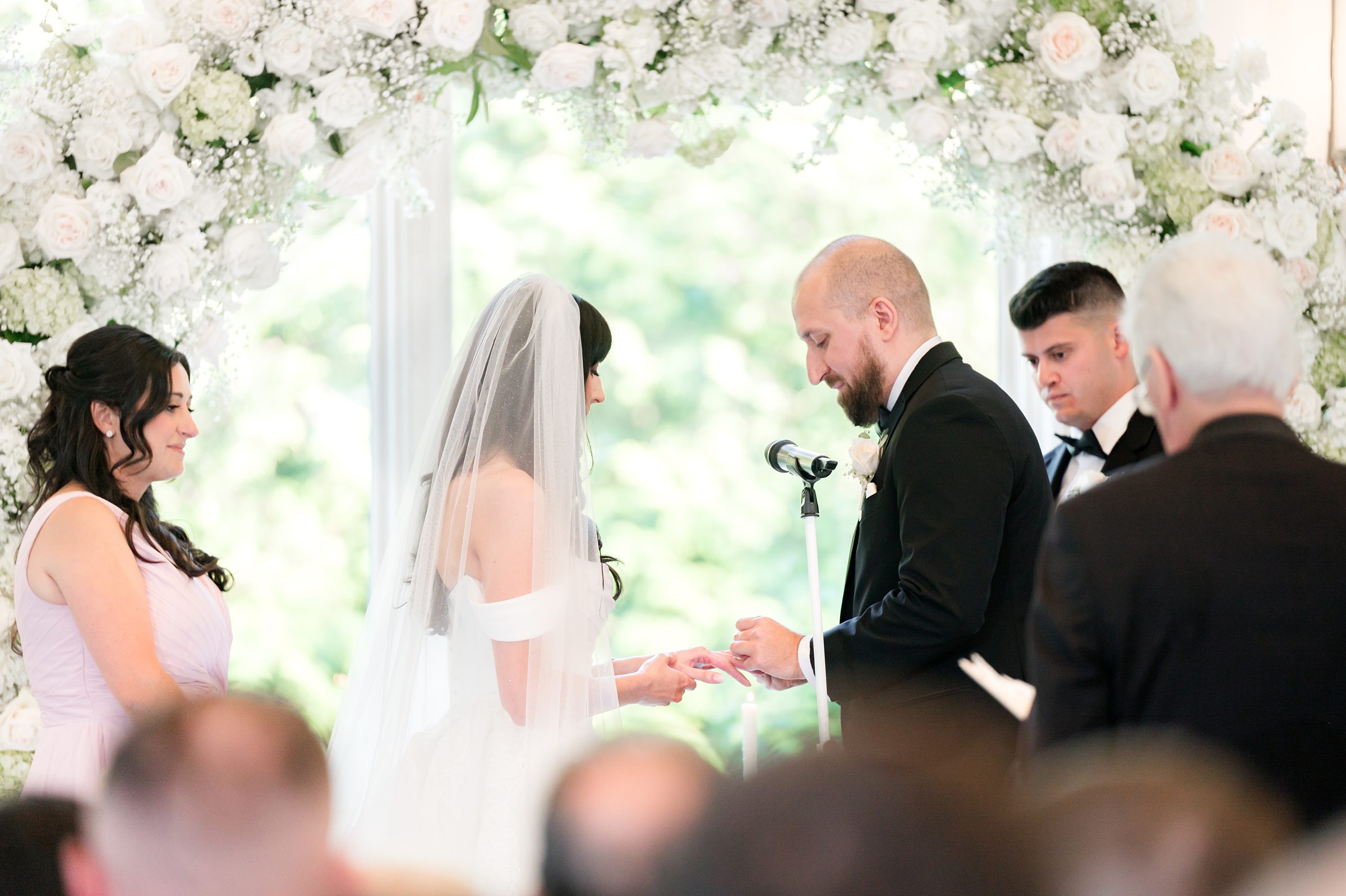bride and groom putting each other's rings at the altar with best man and maid of honor to the side