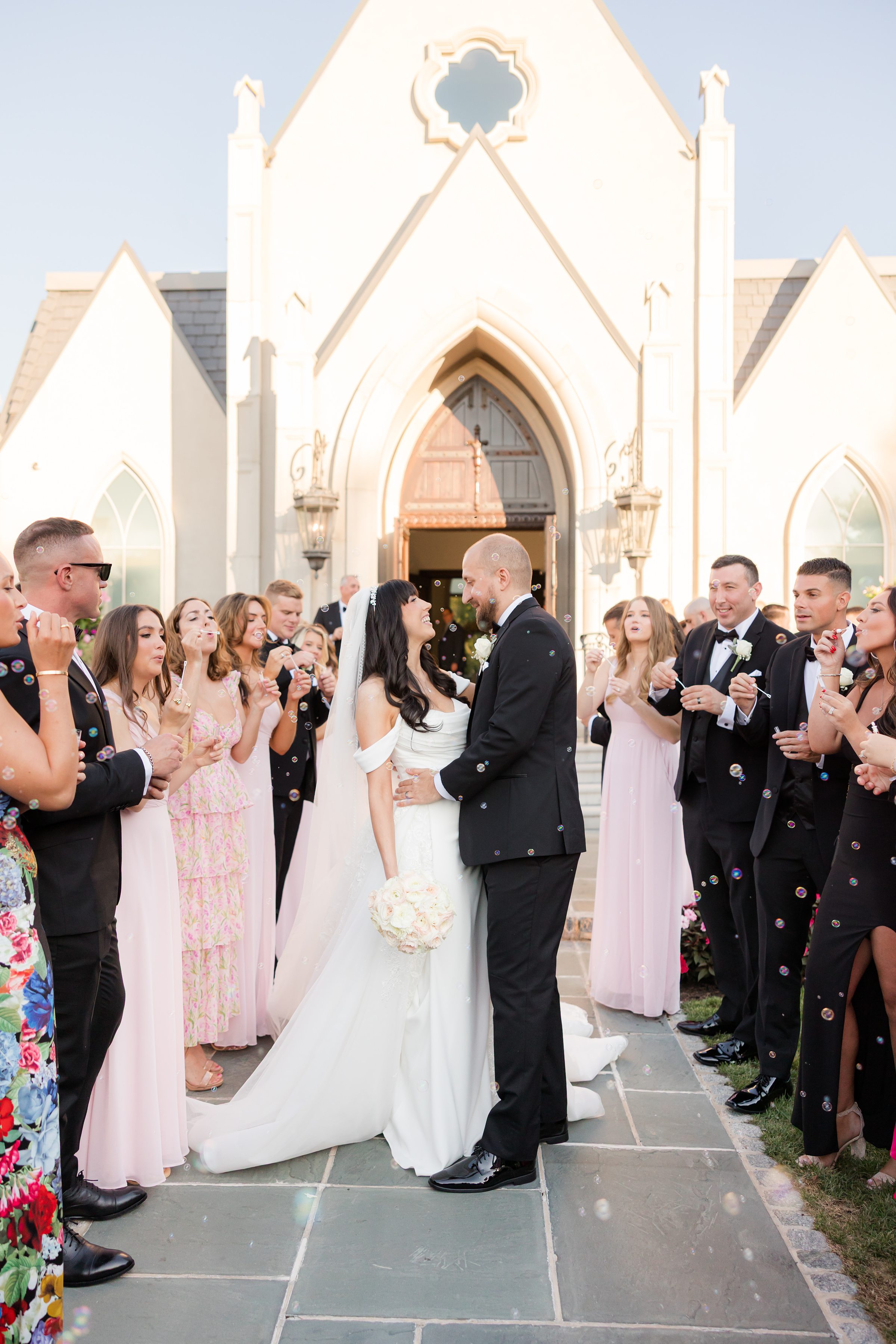 bride and groom looking at each other in the middle of the guests while guests are blowing bubbles