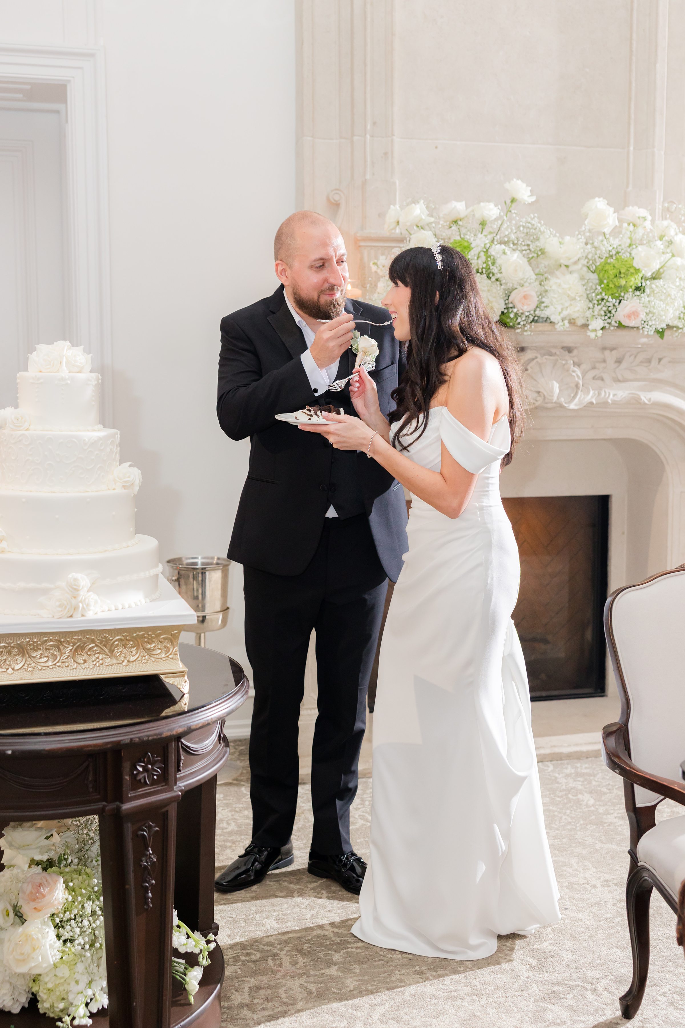 Photo of bride and groom feeding each other the first bite of the cake in front of them