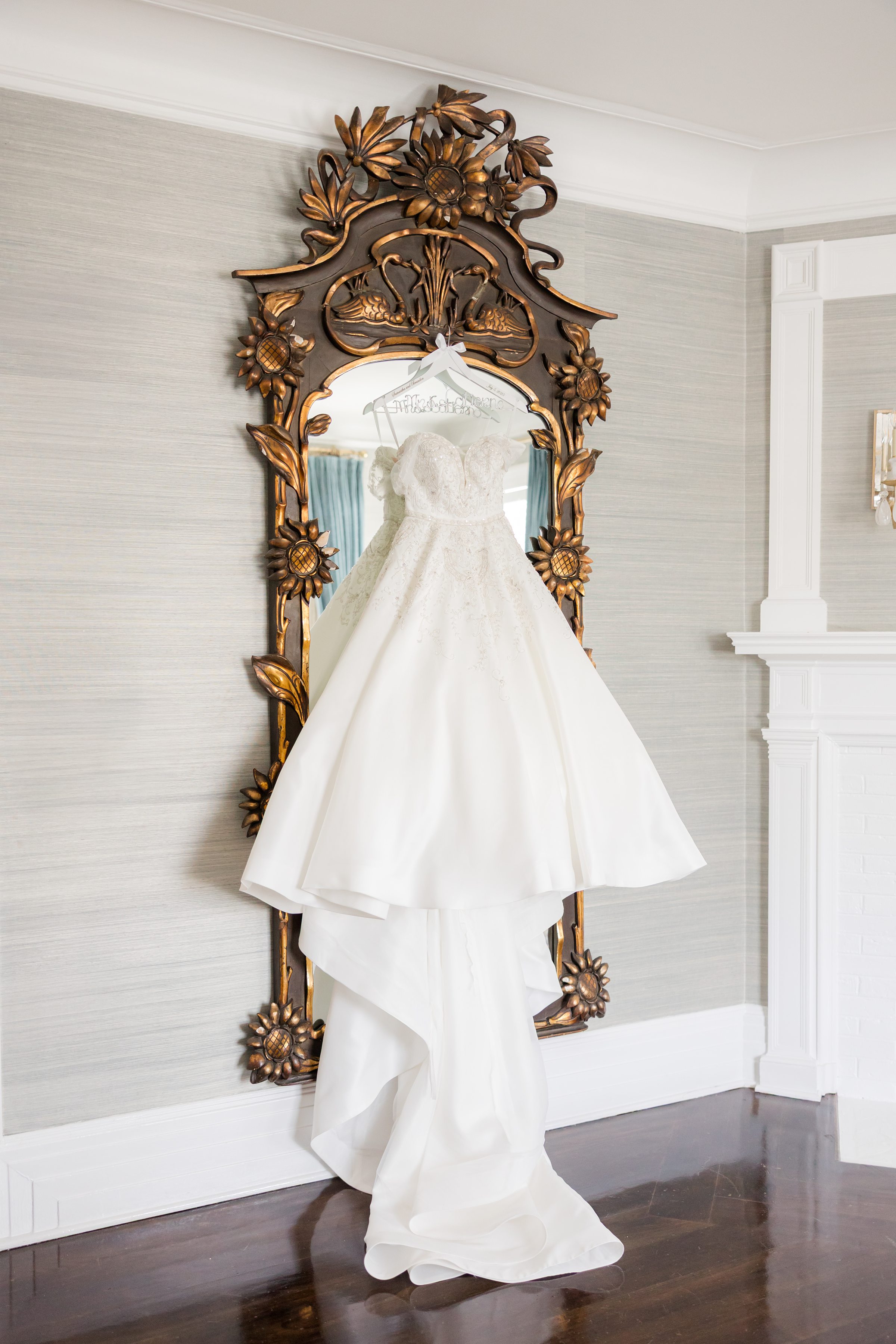 Photo of wedding dress hung on a wooden and brass mirror