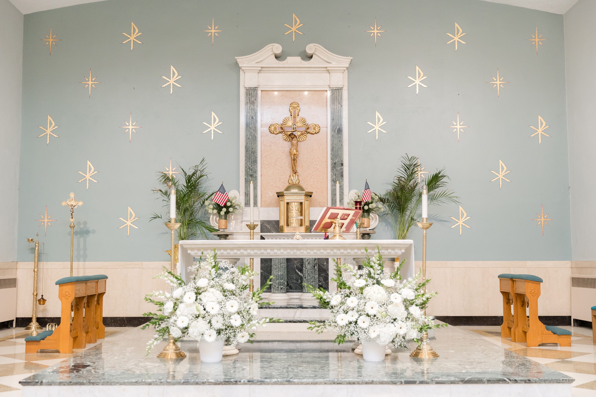 Altar at the Church of Nativity with soft blue-gray and gold accents, and white flowers in front