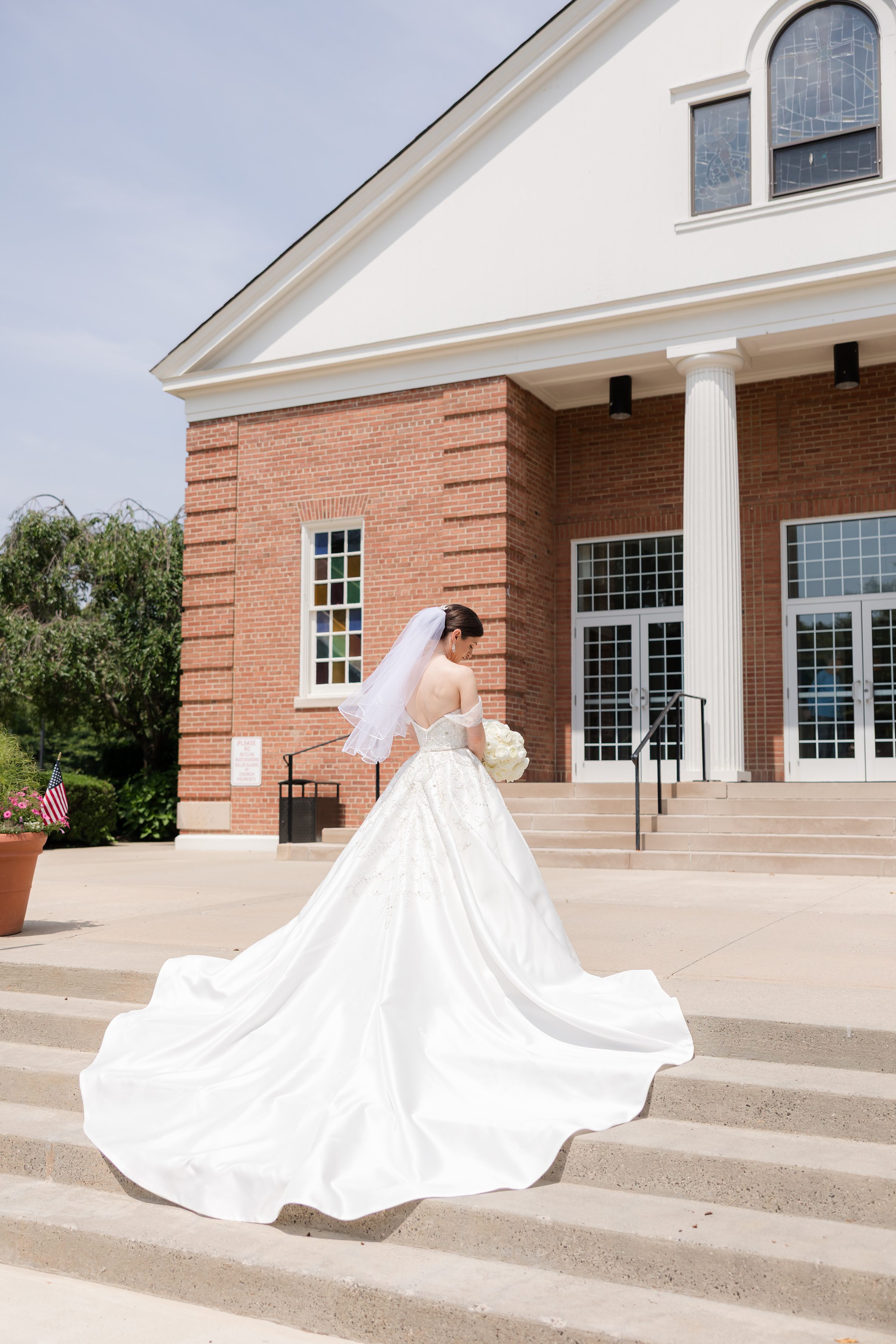 Bride wearing a big white dress with short veil, posing by the stairs, about to enter the Church of Nativity