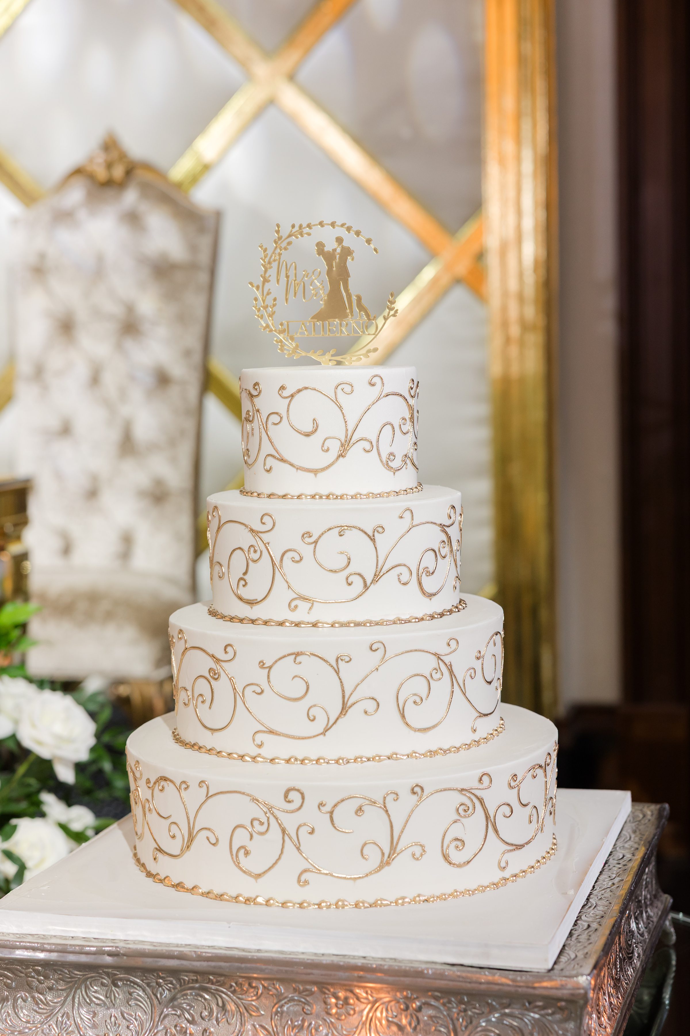 Photo of 4-tier white cake with gold accents and gold topper
