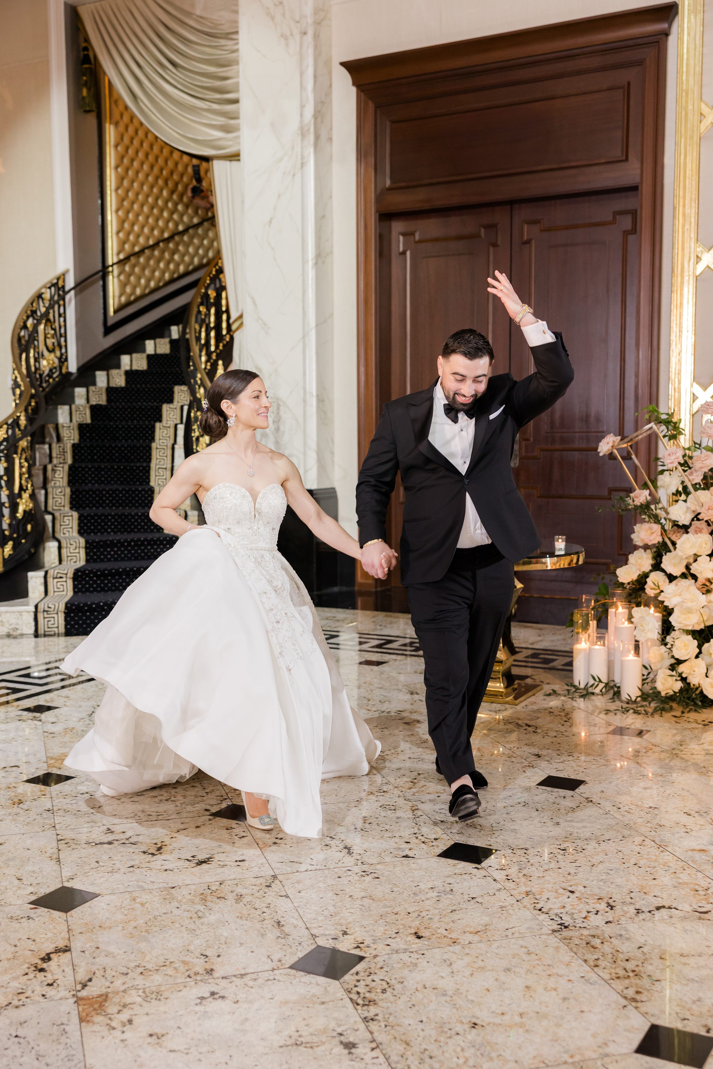 Bride looking at the groom while he has his left hand up and holding her right hand as they enter the reception at Shadowbrook
