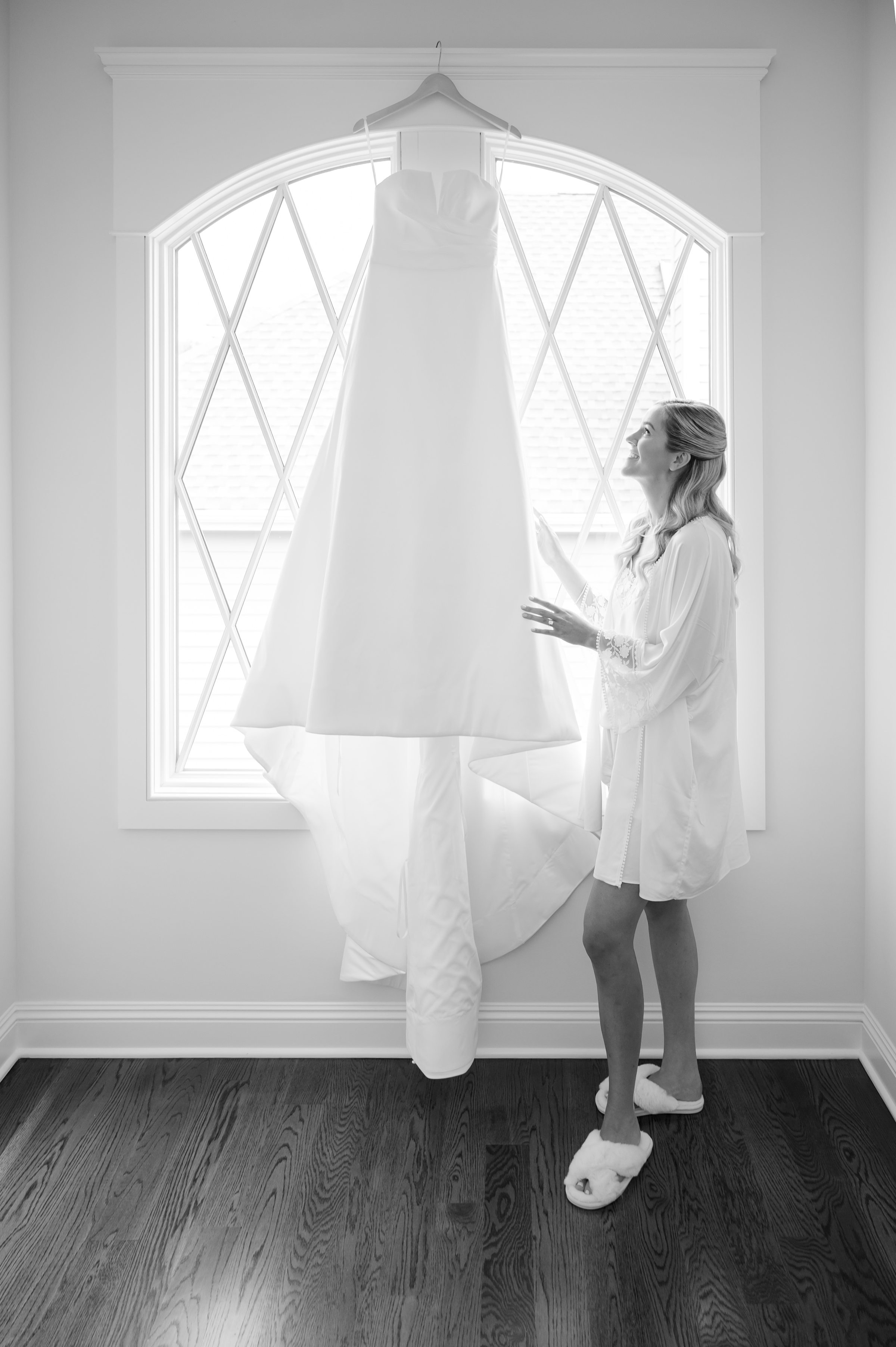 Sunlight pours through the window as the bride’s gown hangs elegantly, a symbol of the beautiful day about to unfold