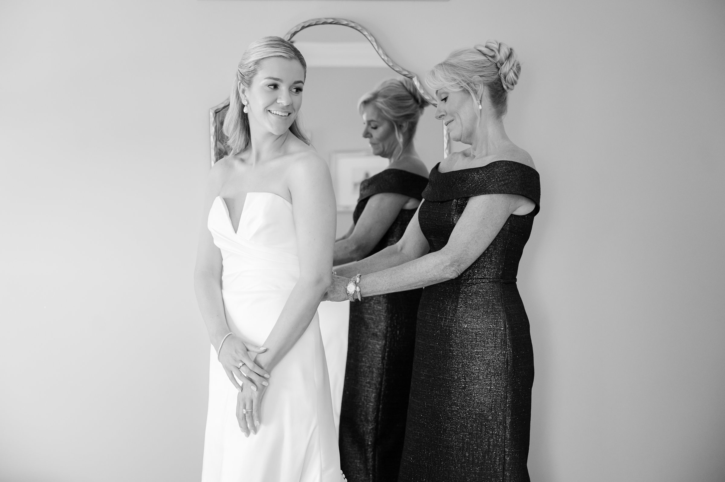 Tender moment shared as a mother lovingly fastens her daughter’s dress, their hearts quietly celebrating this once-in-a-lifetime day.