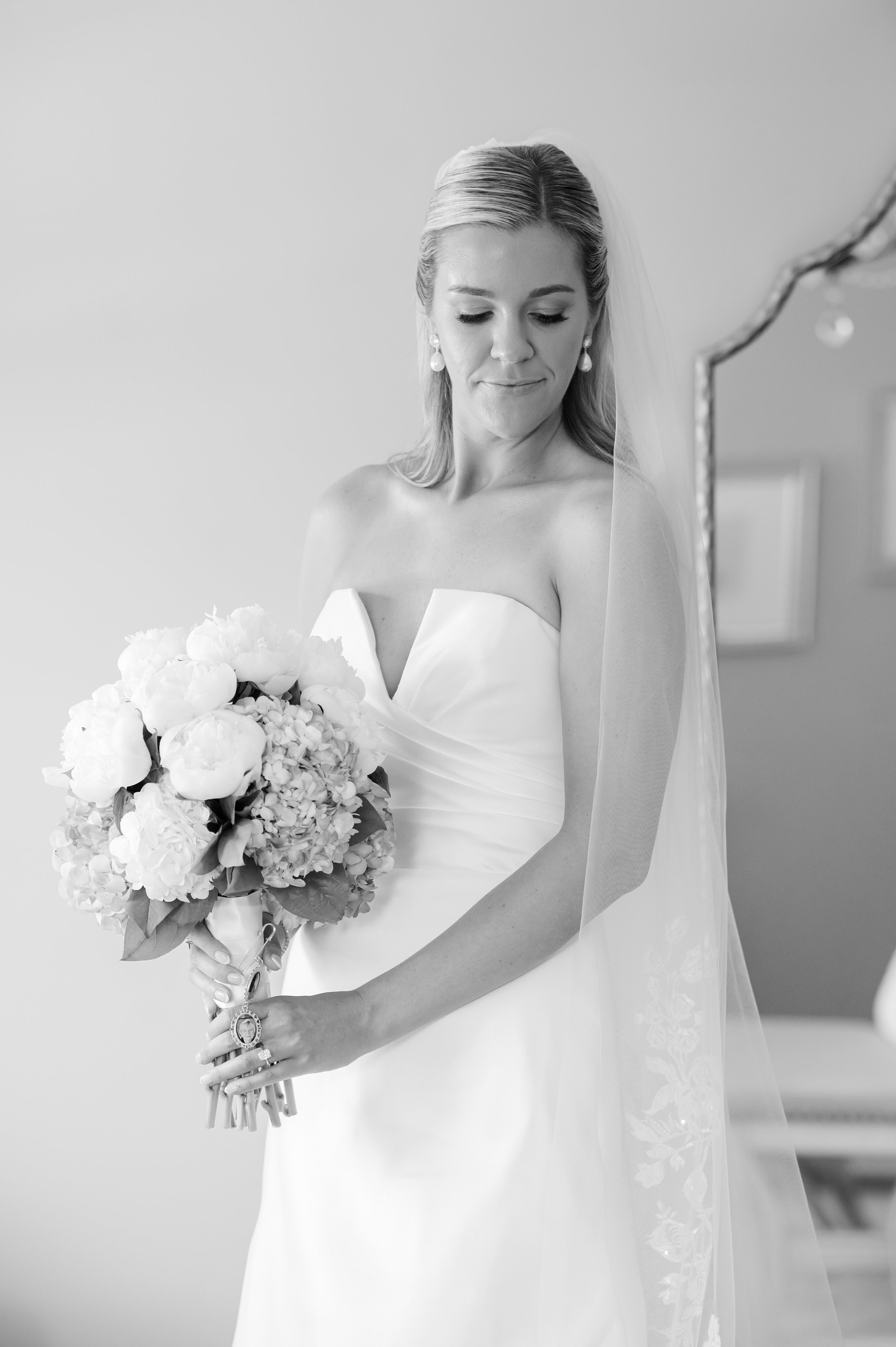 Bride gazes softly at her bouquet, wrapped in quiet anticipation as she stands on the threshold of forever.”