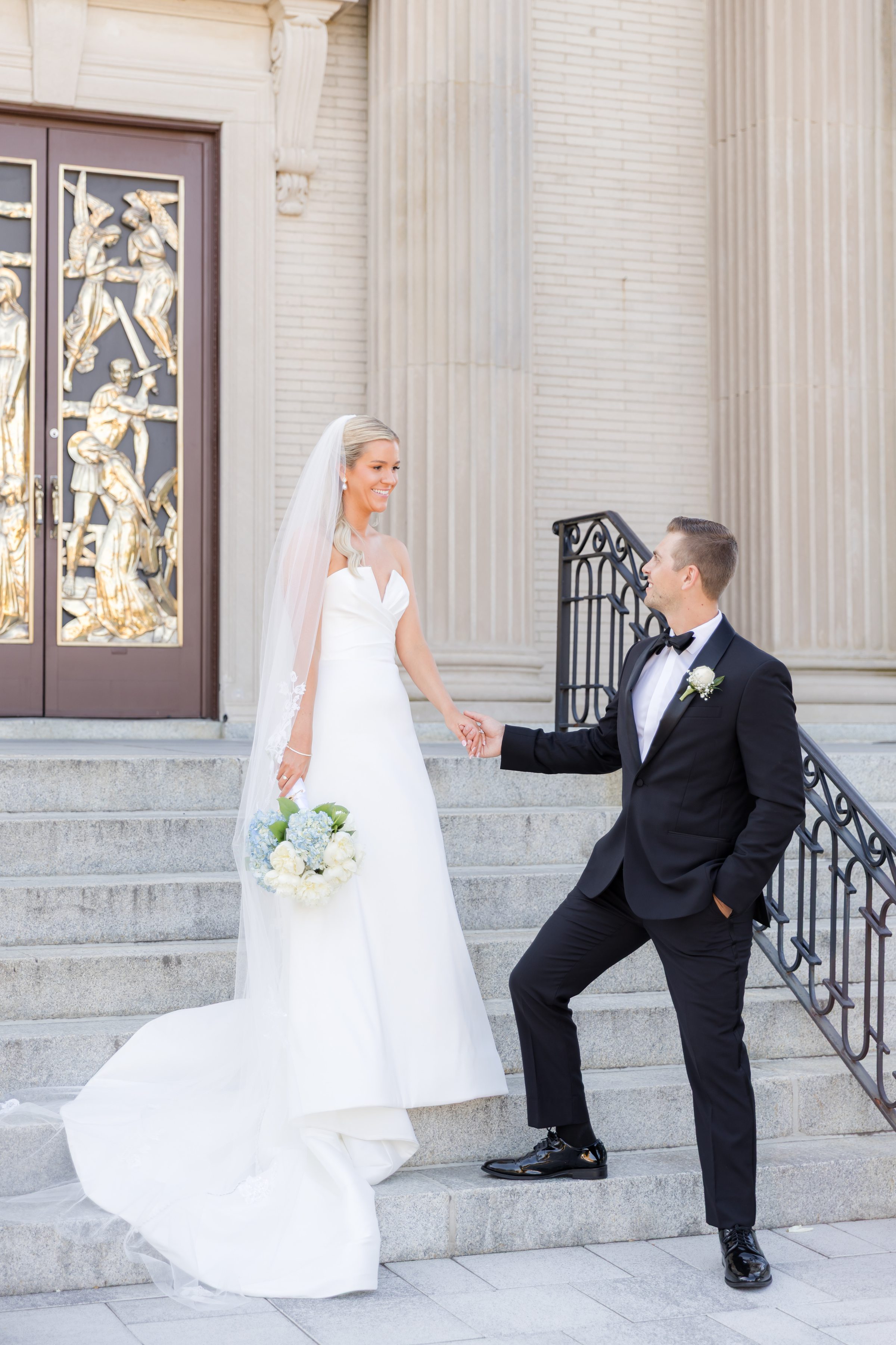 Bride and groom share a quiet, joyful moment on the church steps, smiling at each other as they begin their new life together