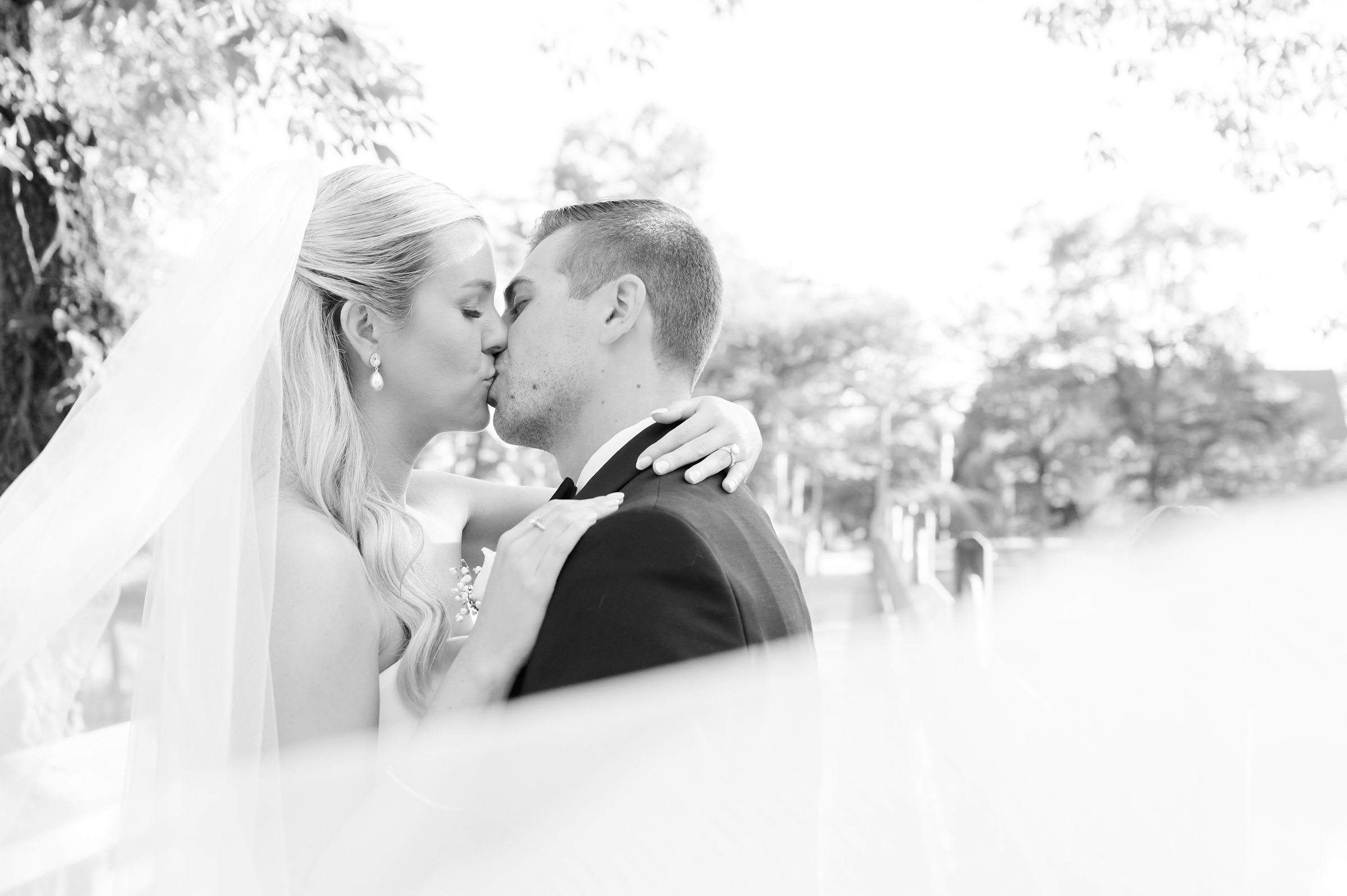 Bride and groom share a soft, intimate kiss, wrapped in each other’s arms and lost in quiet romance.