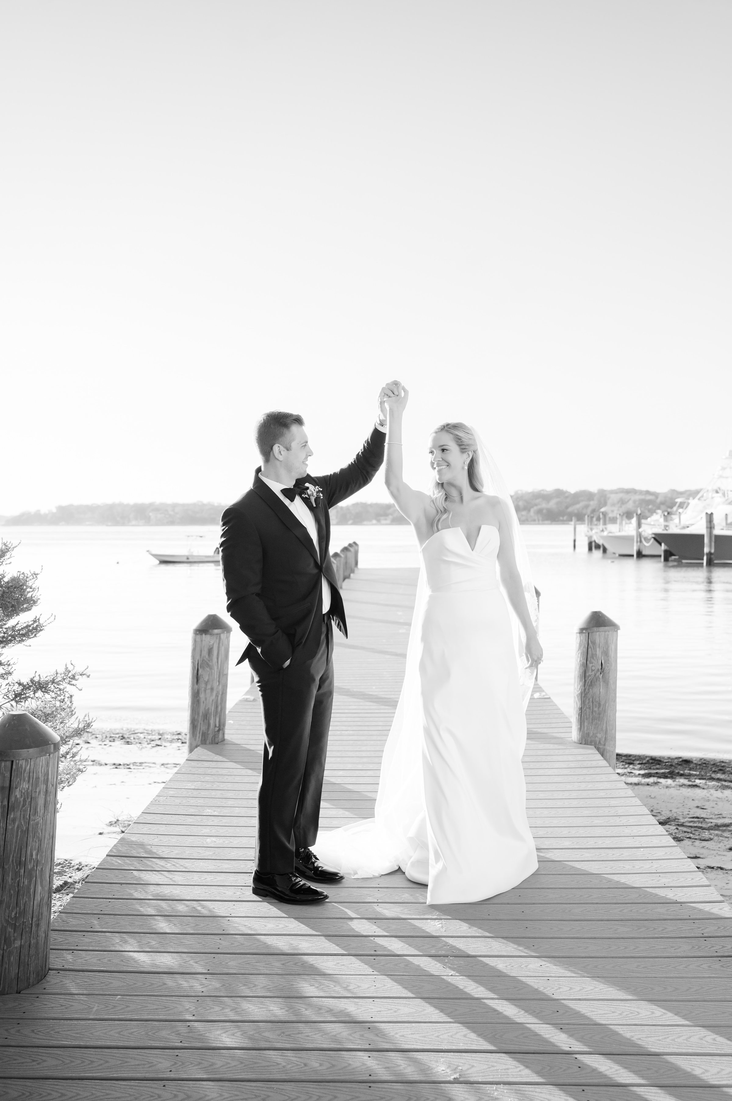 Bride and groom share a quiet, intimate moment on a dock, framed by water and timeless romance