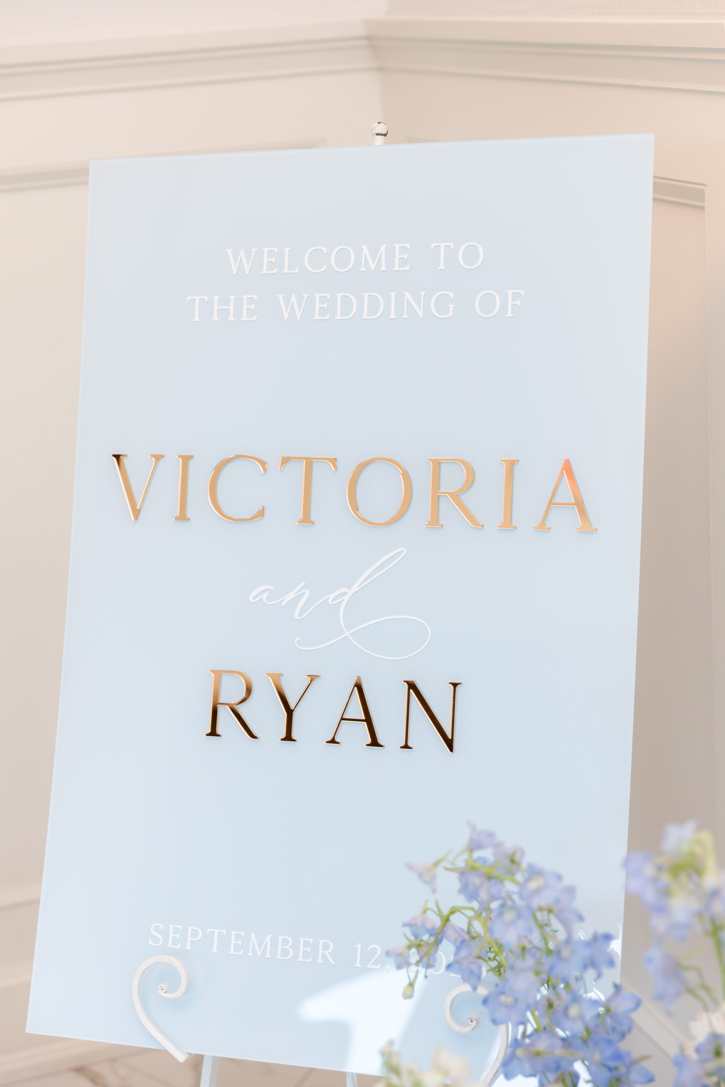 Romantic welcome sign in soft blue and gold lettering introduces a love story just beginning.