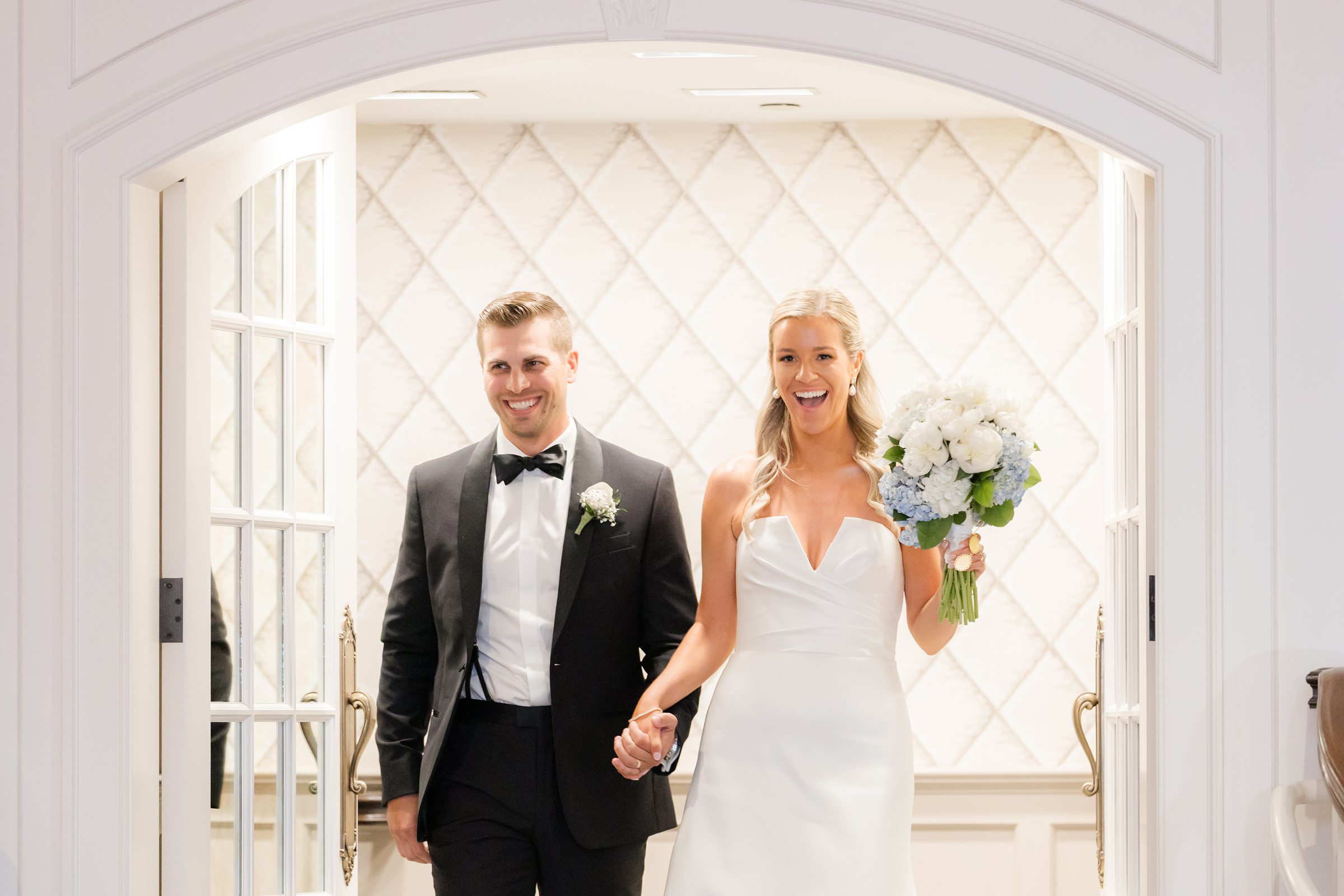 Groom glances at the bride with a soft smile, clearly captivated by her as they enter together.