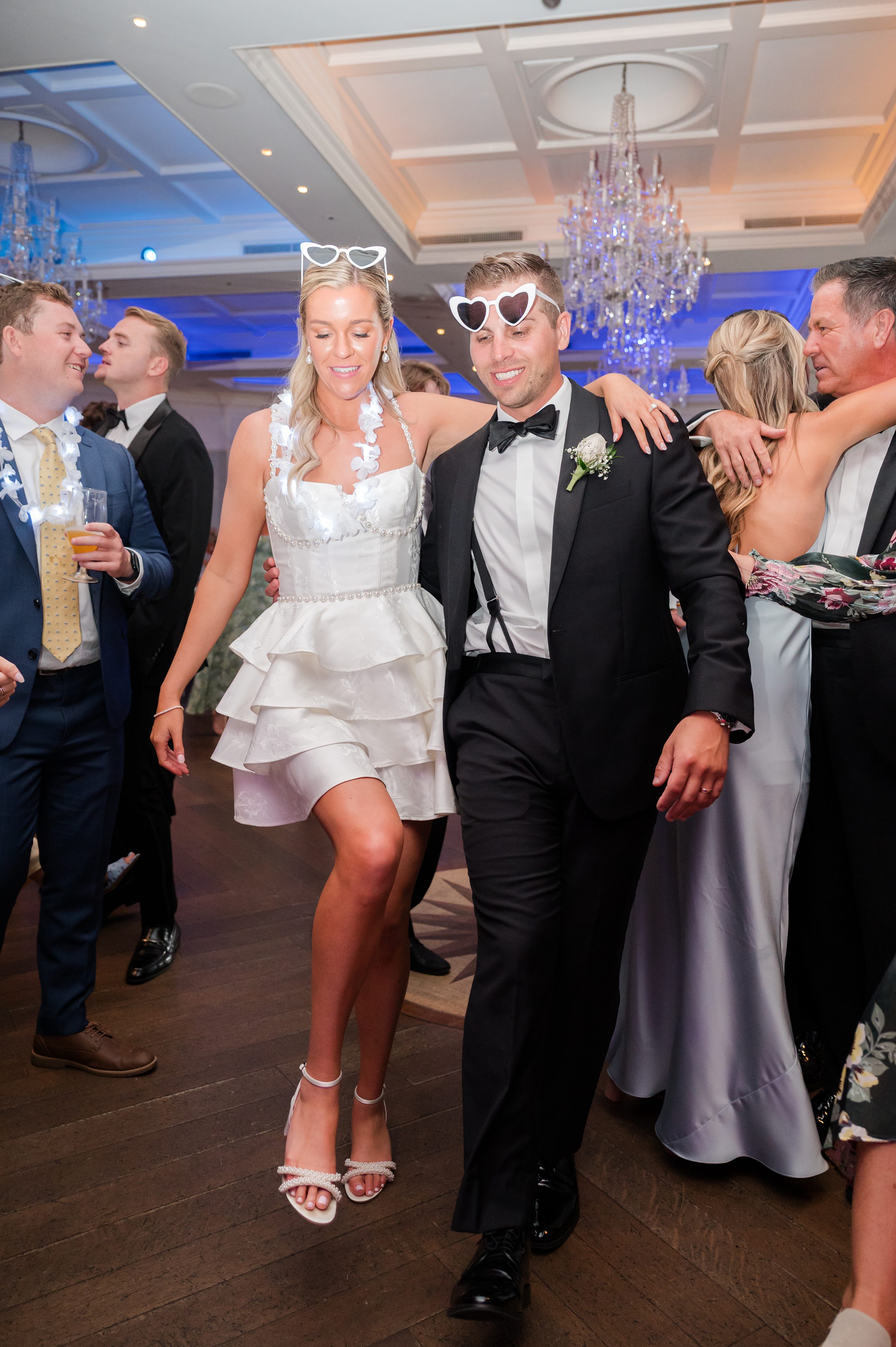 Bride and groom walk closely together, their connection evident as they smile and enjoy the celebration