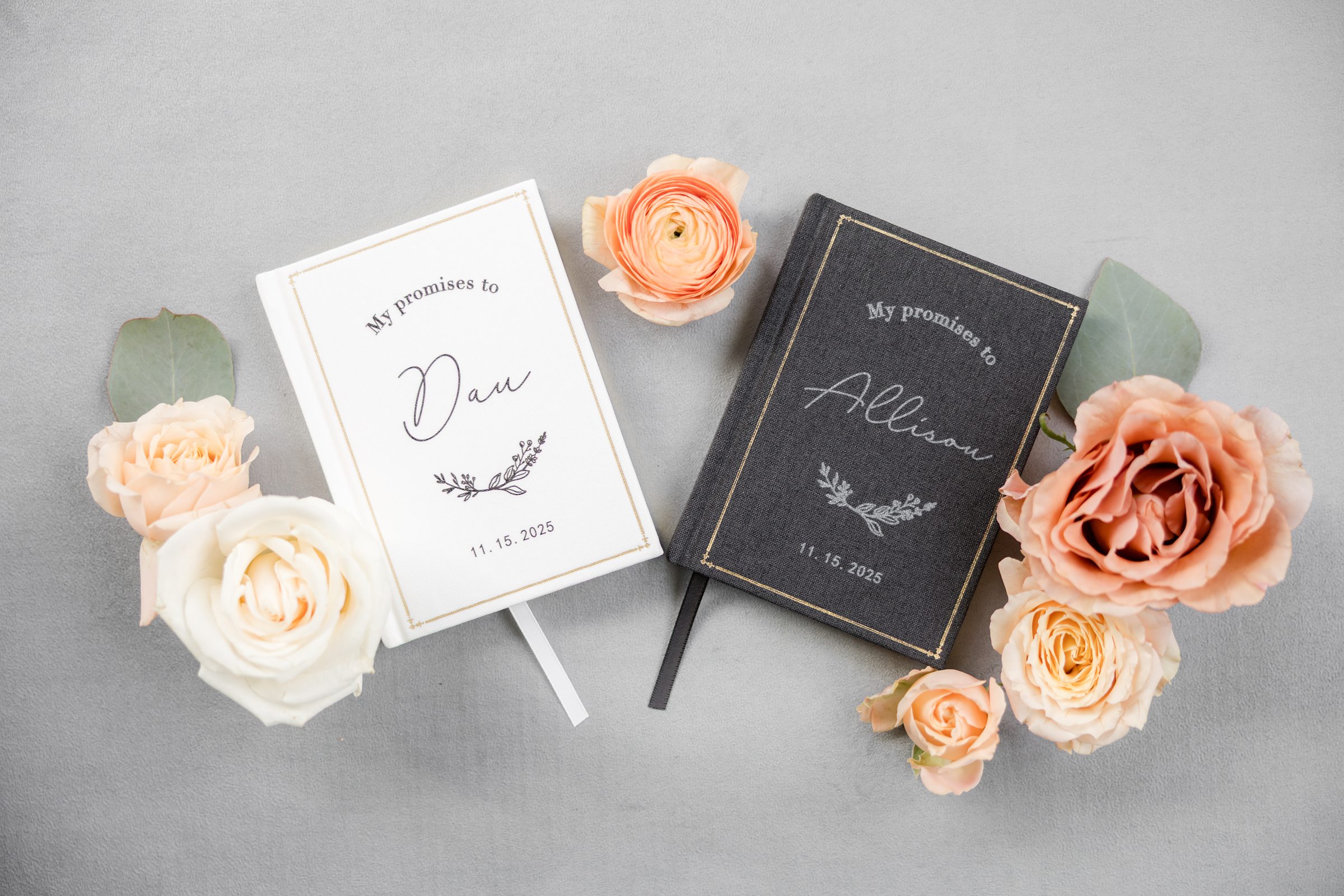 Two vow books labeled with the couple’s names and wedding date, styled with soft colored roses