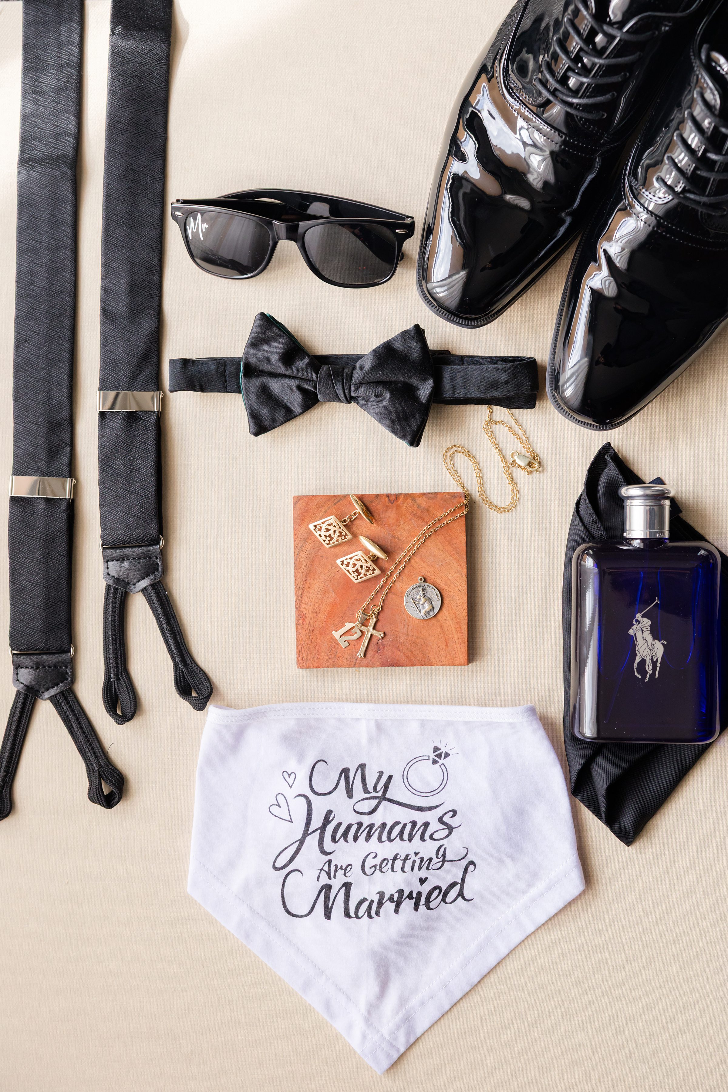 Groom’s black patent shoes, suspenders, bow tie, sunglasses, cologne, jewelry, and a white bandana reading