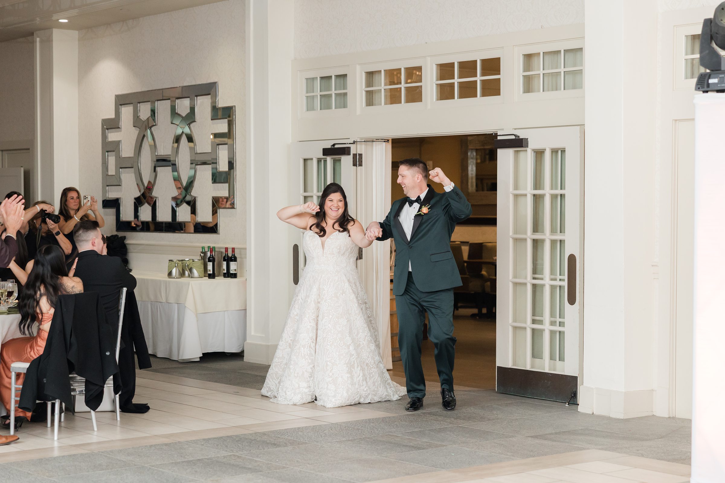 Bride and groom make a joyful entrance into the reception space with raised arms