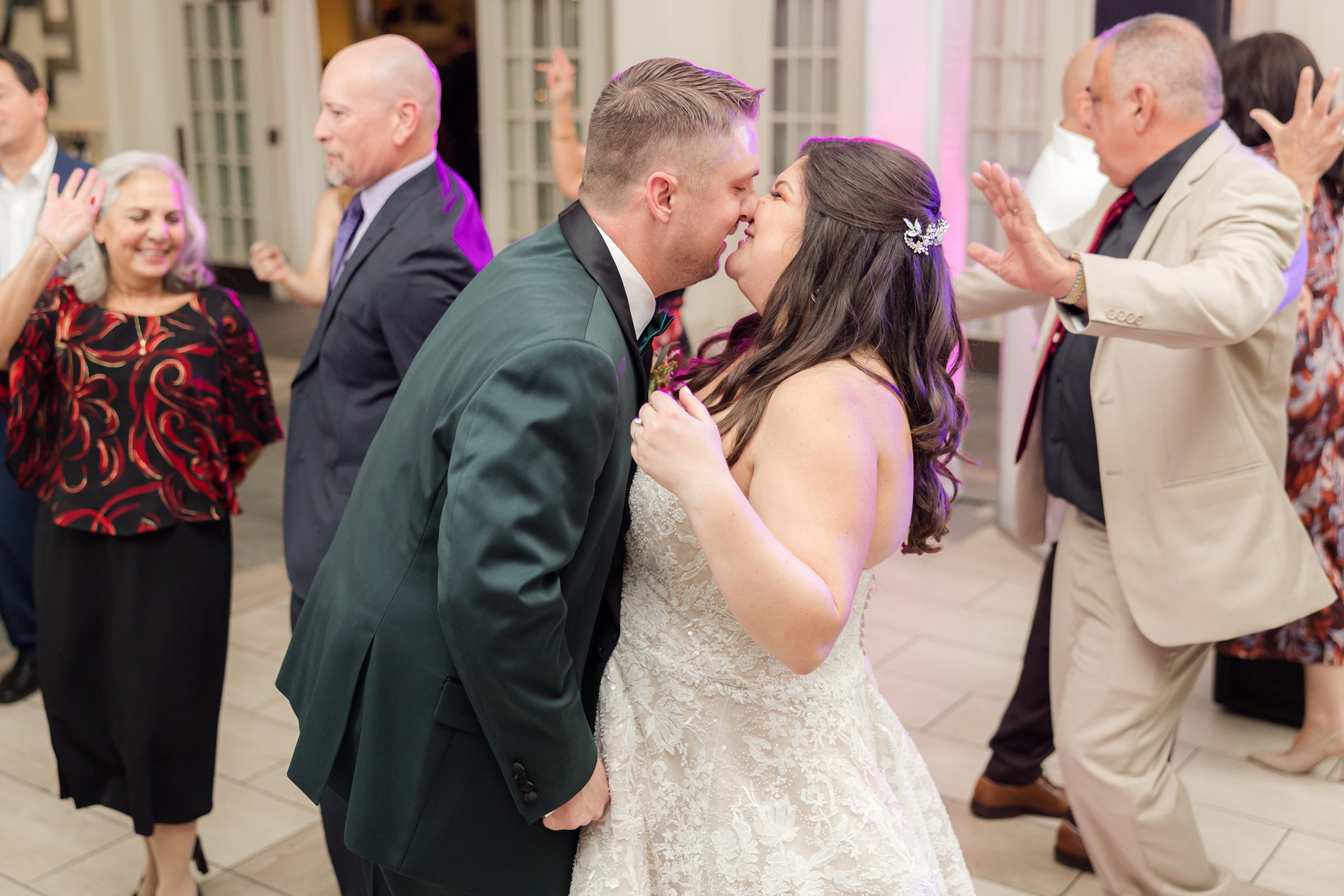 Bride and groom share a kiss on the dance floor while guests dance around them