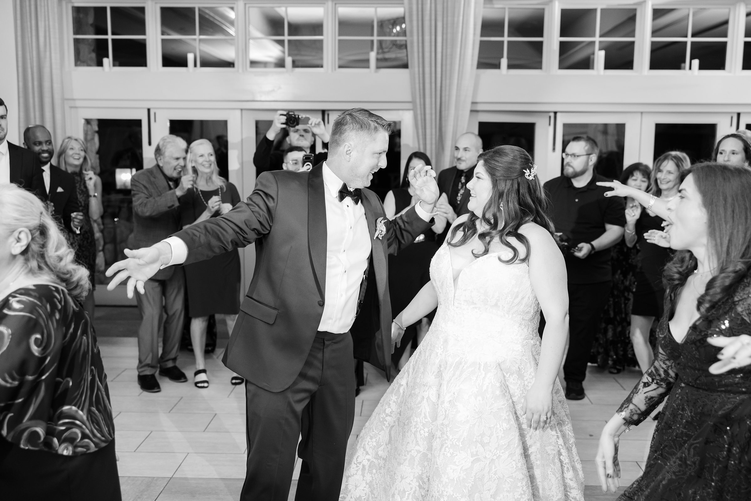 Bride and groom dance surrounded by cheering guests on the reception floor
