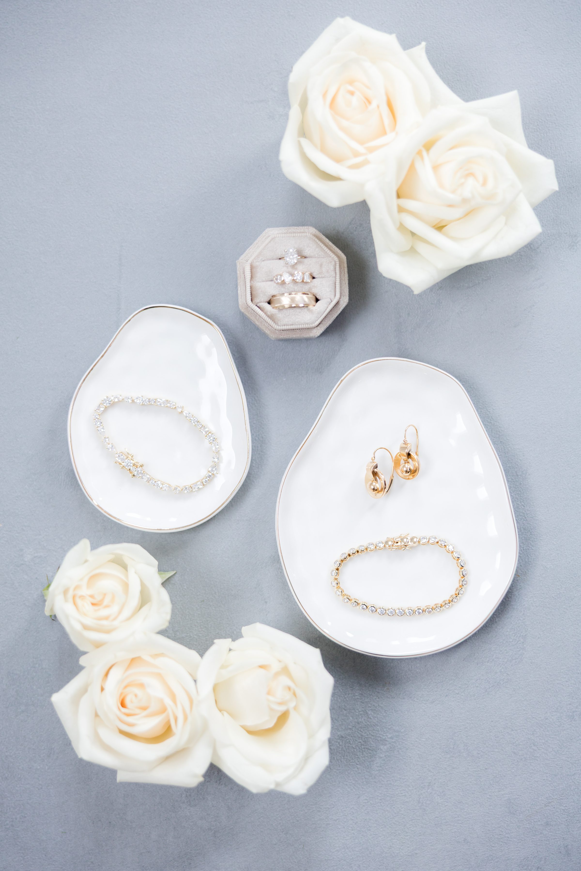 Bridal jewelry including rings, bracelet, and earrings with white roses.