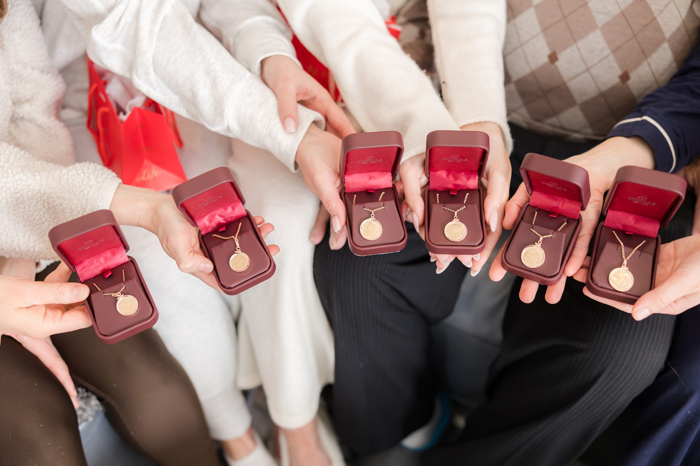 Bridesmaids holding matching gold necklaces in velvet boxes, a sweet and meaningful gift shared before the wedding day.