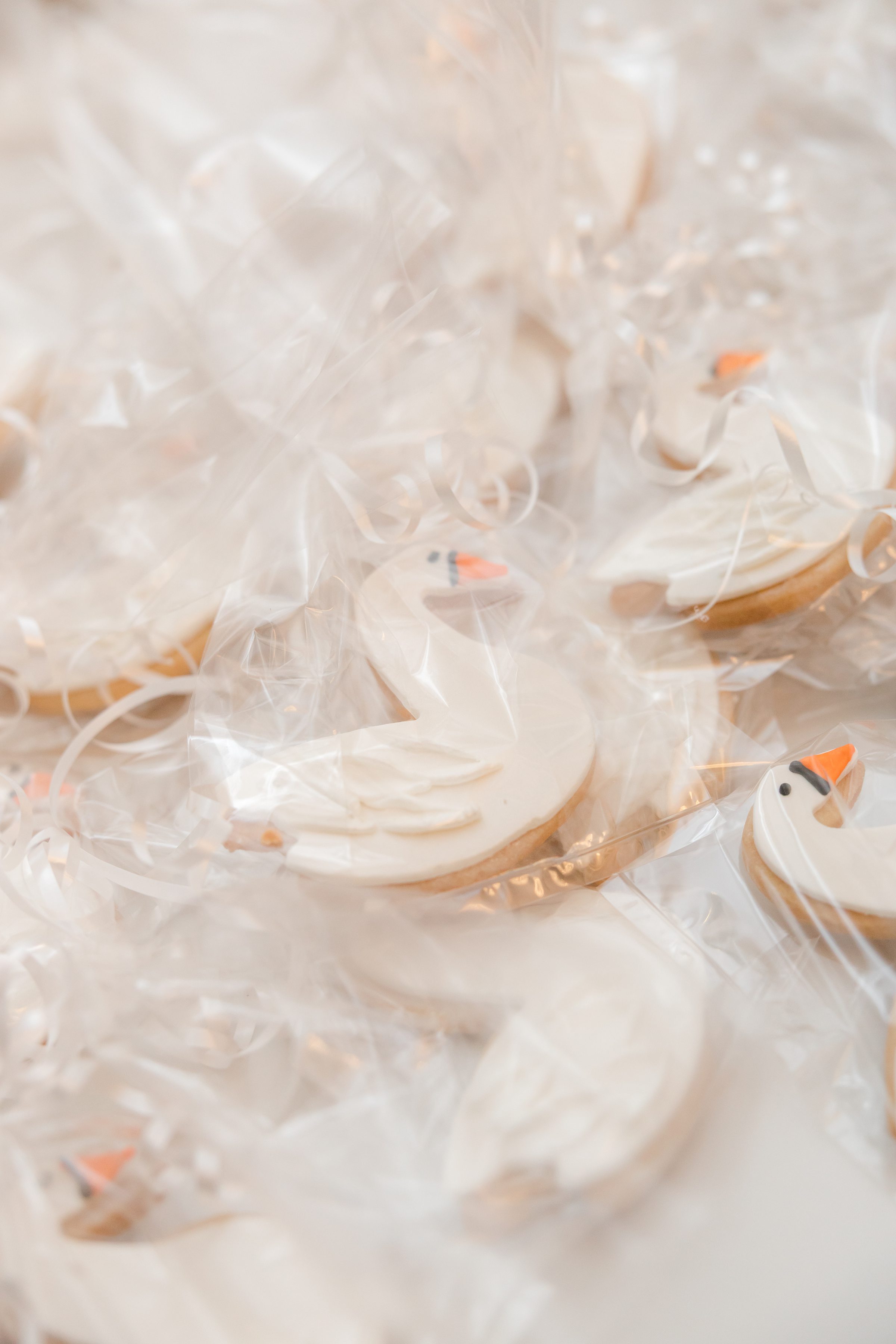 Wrapped wedding cookies decorated as white swans with orange beaks.
