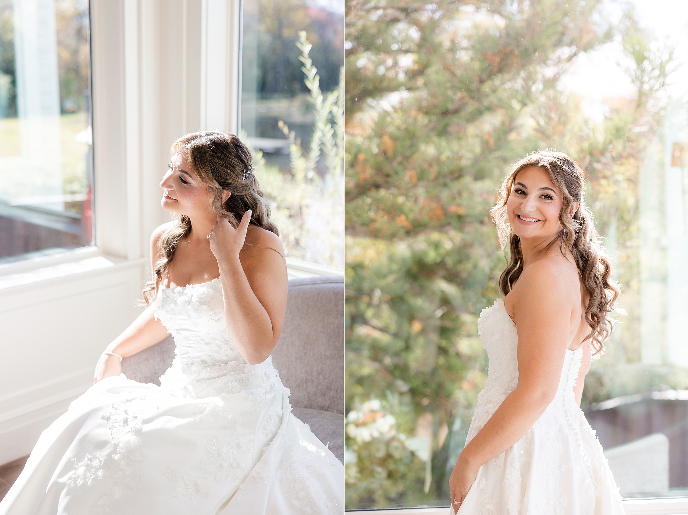 Bride sitting by a window adjusting her hair and smiling in soft natural light.