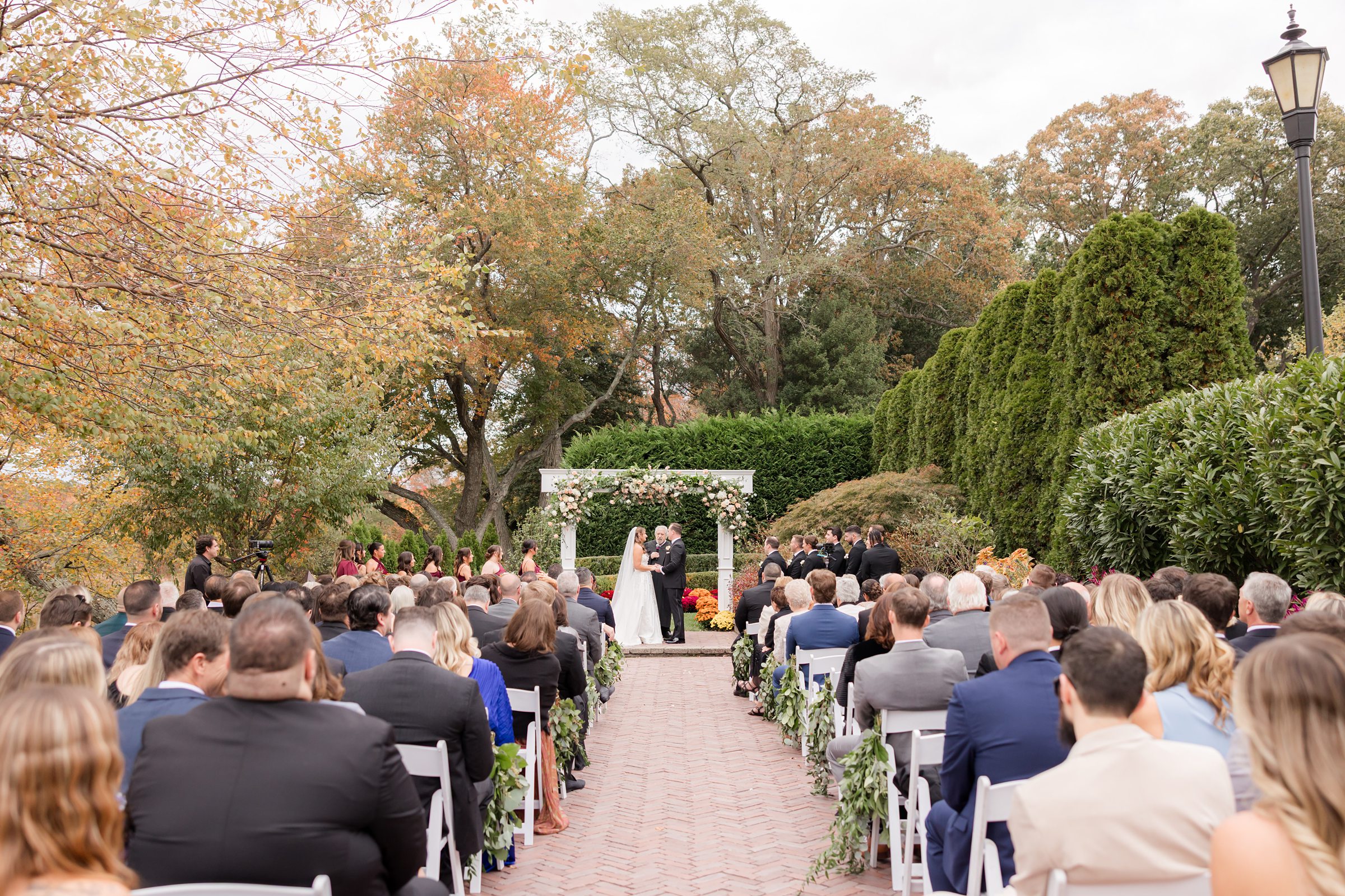 Wide shot of outdoor wedding ceremony with seated guests facing the couple at the altar.