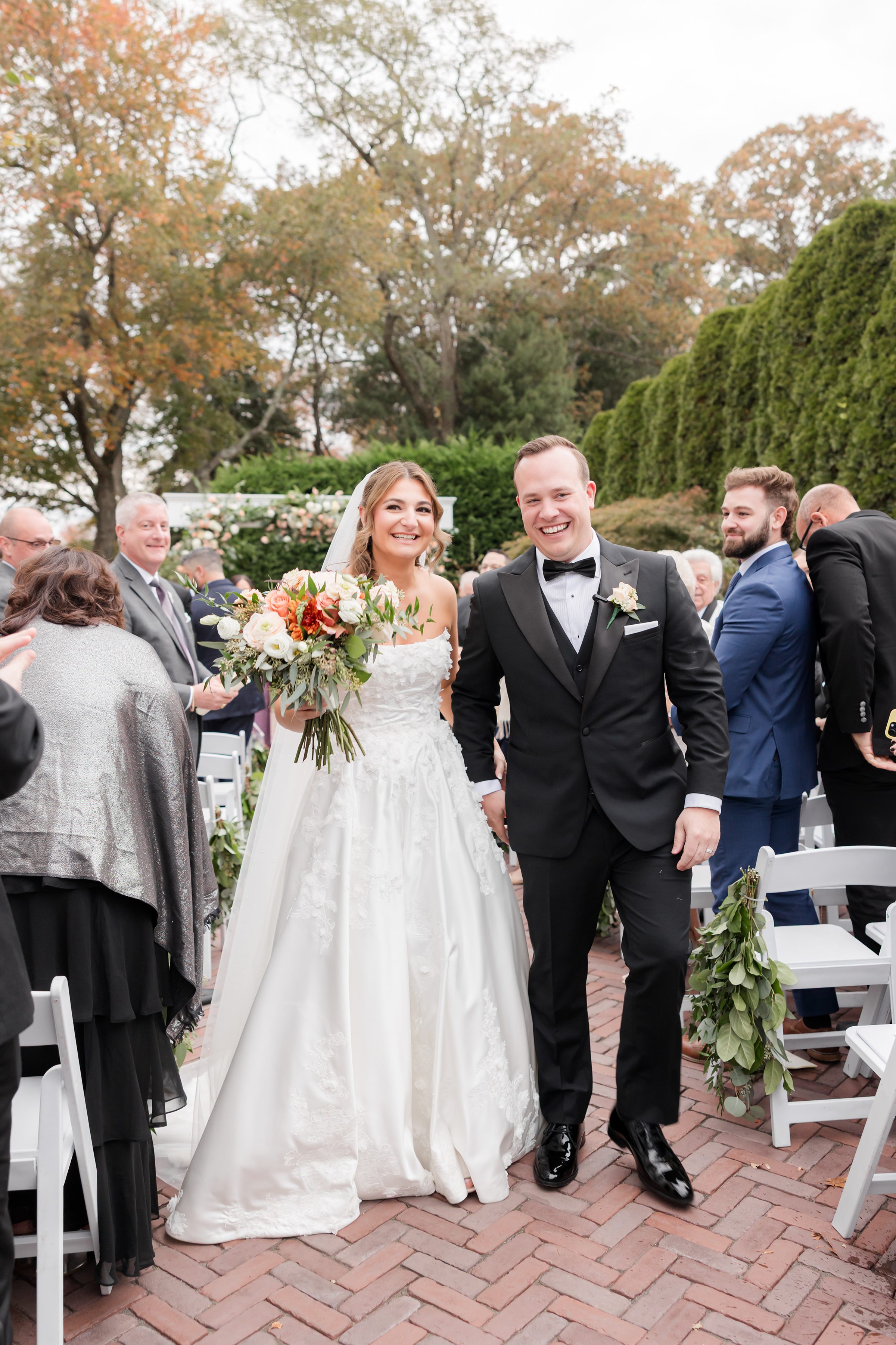 Newlyweds walking down the aisle smiling and holding hands after the ceremony.