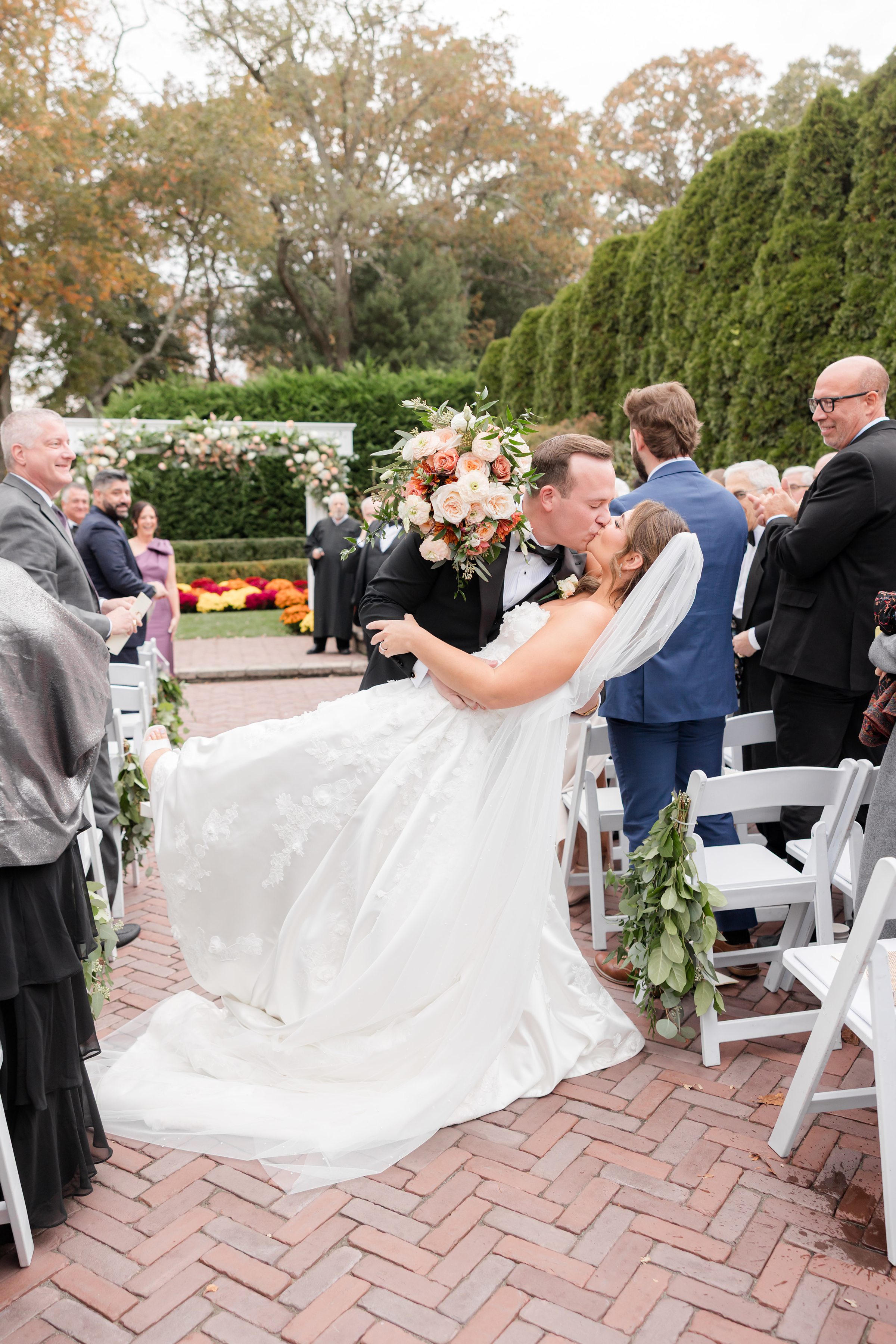 Groom dipping the bride for a kiss during the ceremony as guests watch and applaud.