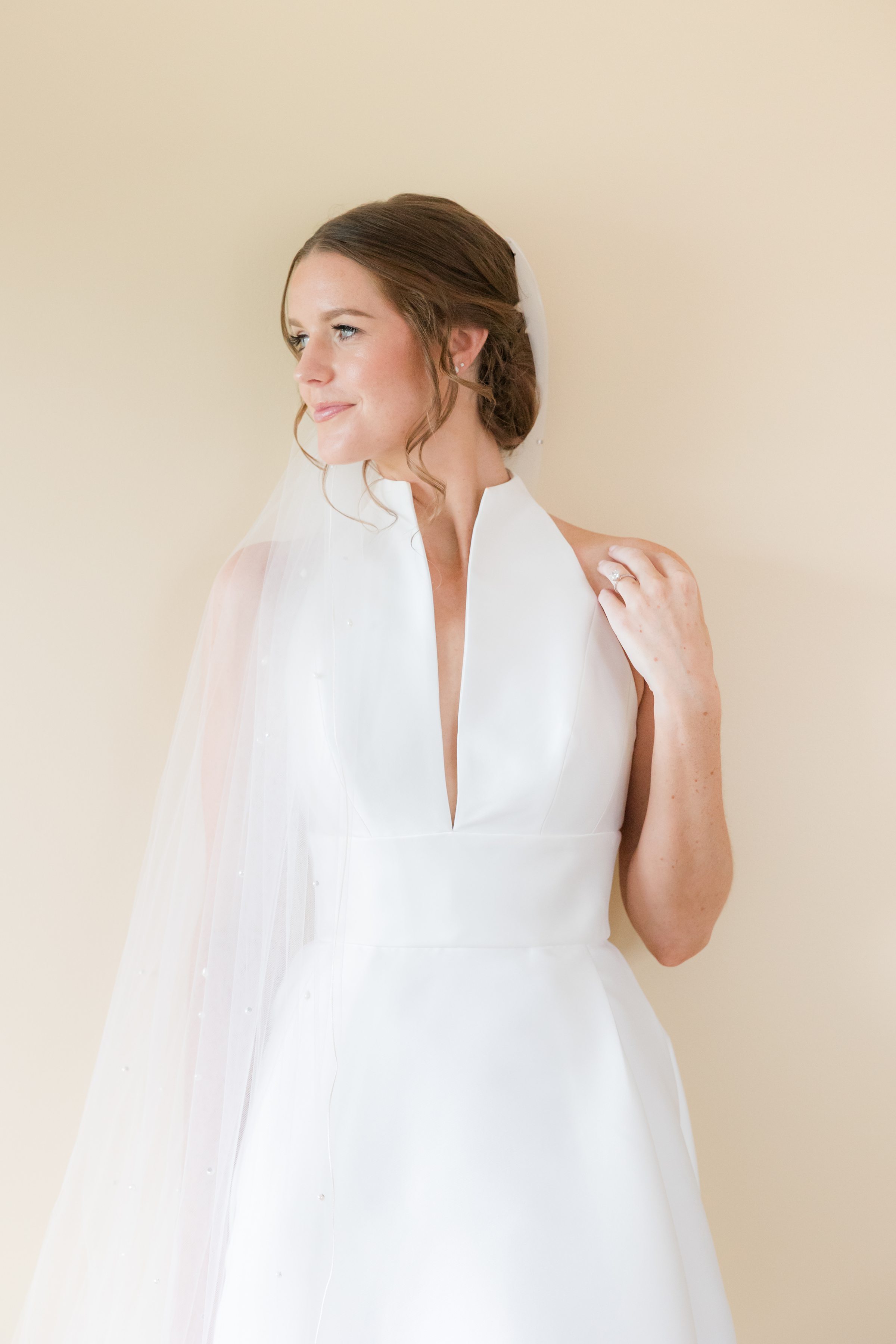 Soft, glowing portrait of the bride, her veil cascading gently as she gazes with calm anticipation.