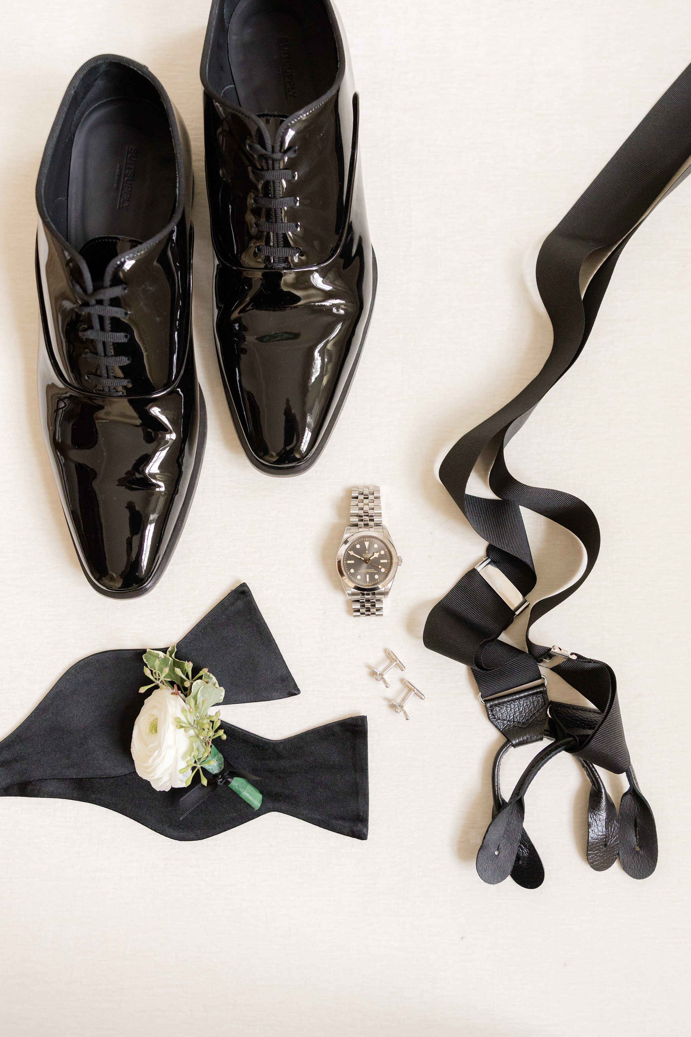 Groom’s attire—sleek shoes, cufflinks, and watch—carefully arranged for a timeless look.