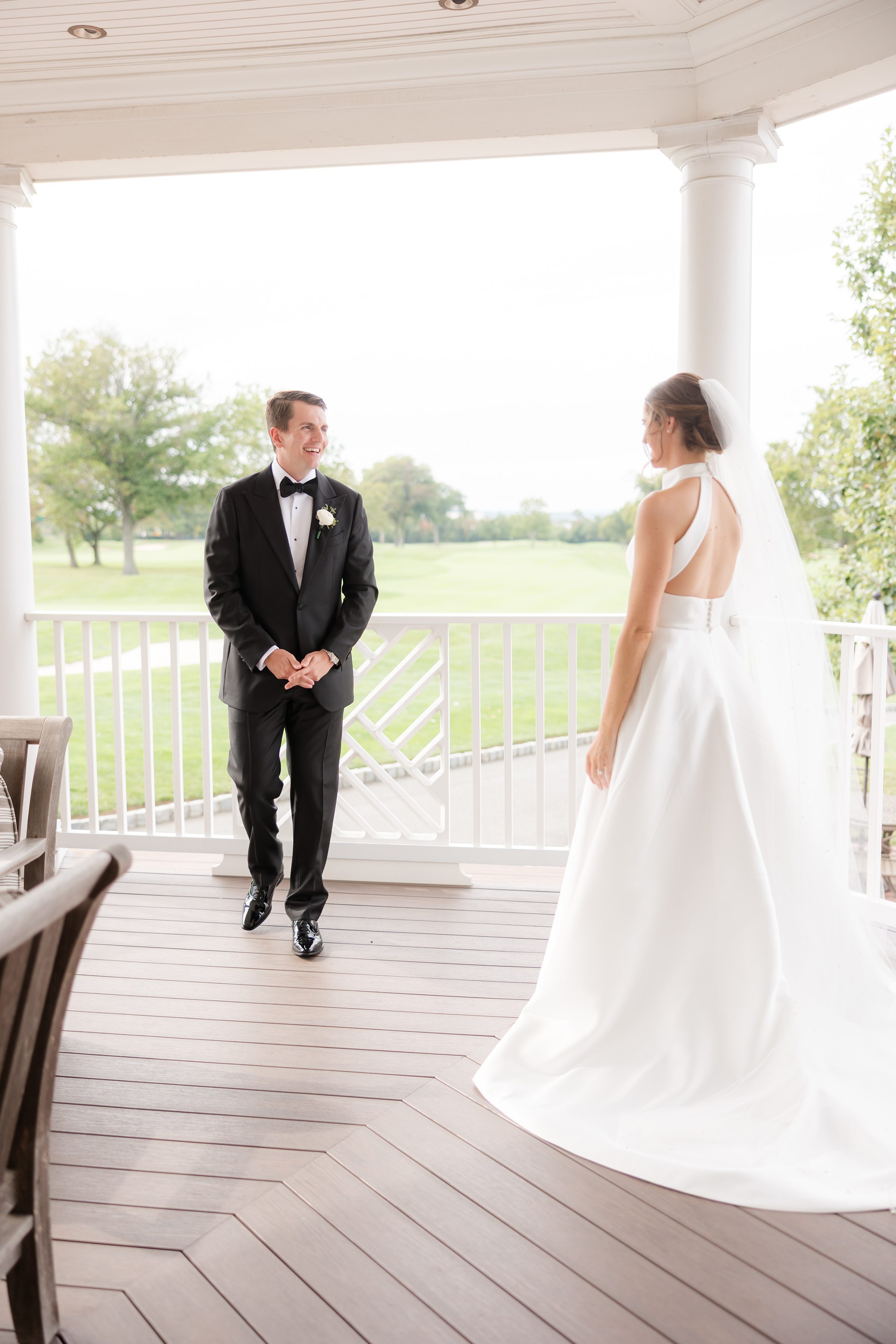 Groom turns toward his bride on a sunlit porch, their first look filled with anticipation and quiet joy